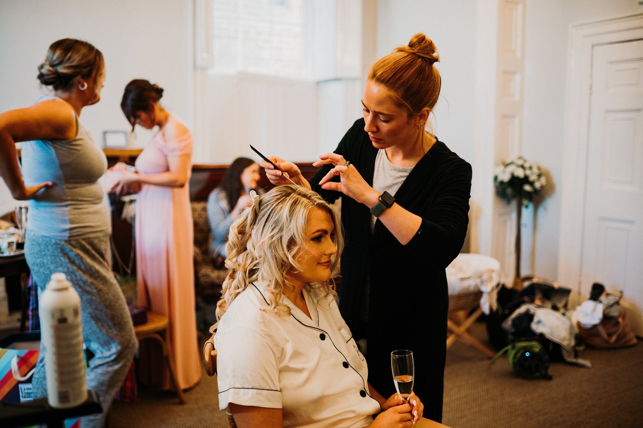 The bride has her hair done on the morning of their wedding.