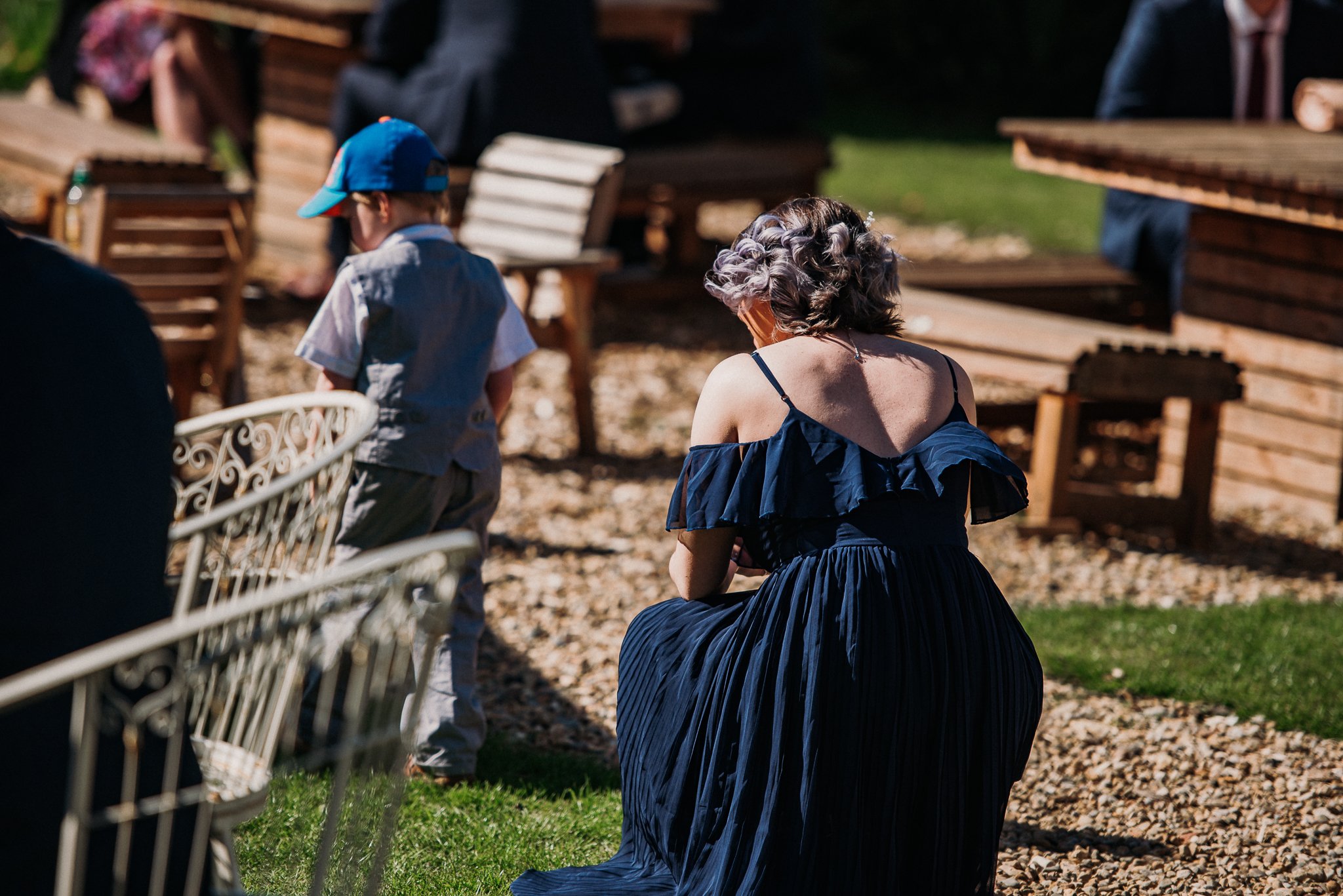 A bridemaid crouches down to see a young wedding guest at Sneaton Castle, Whitby.