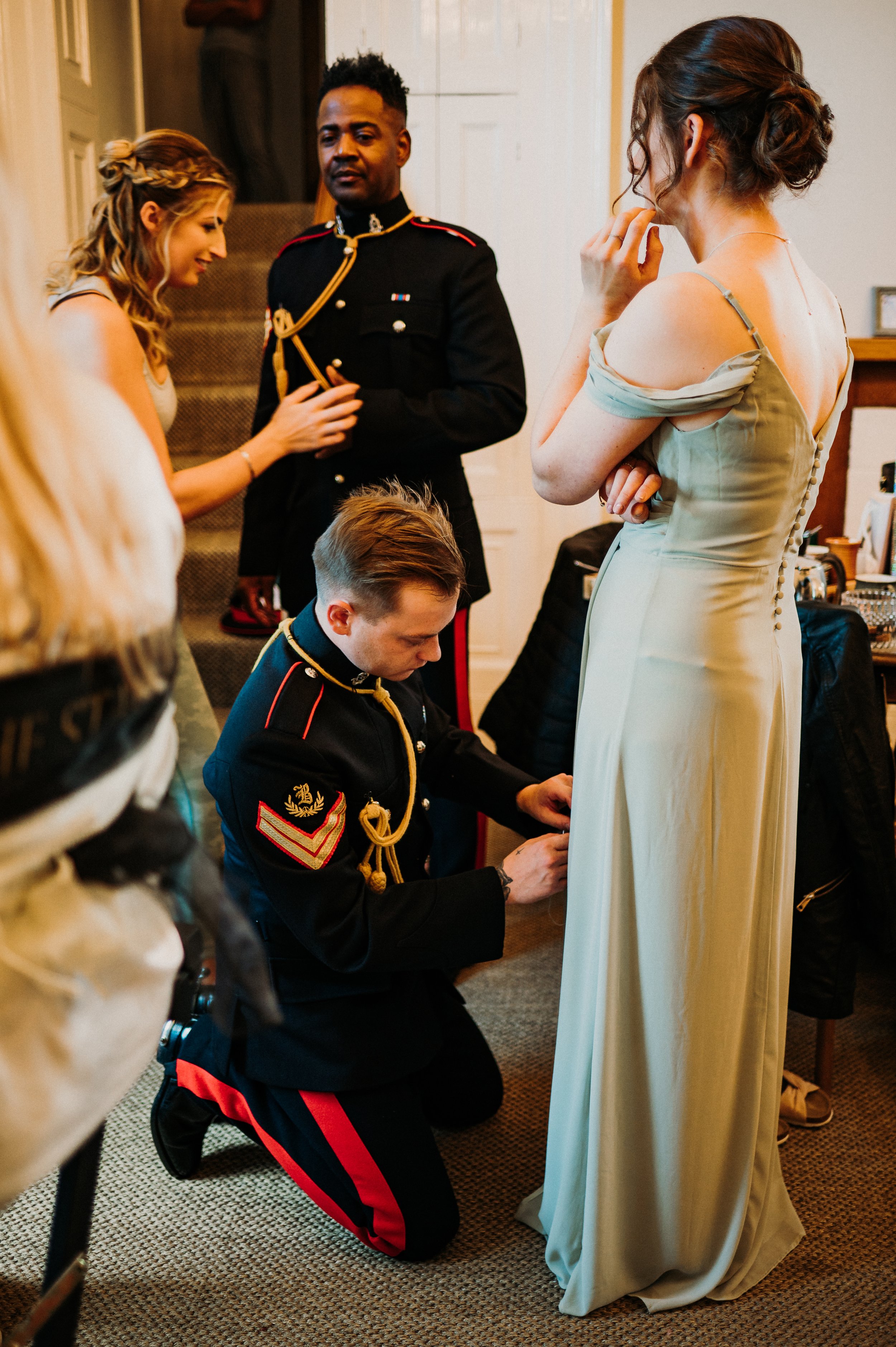 One of the groom's sword guard helps a bridesmaid to repair her dress on the morning of the wedding.