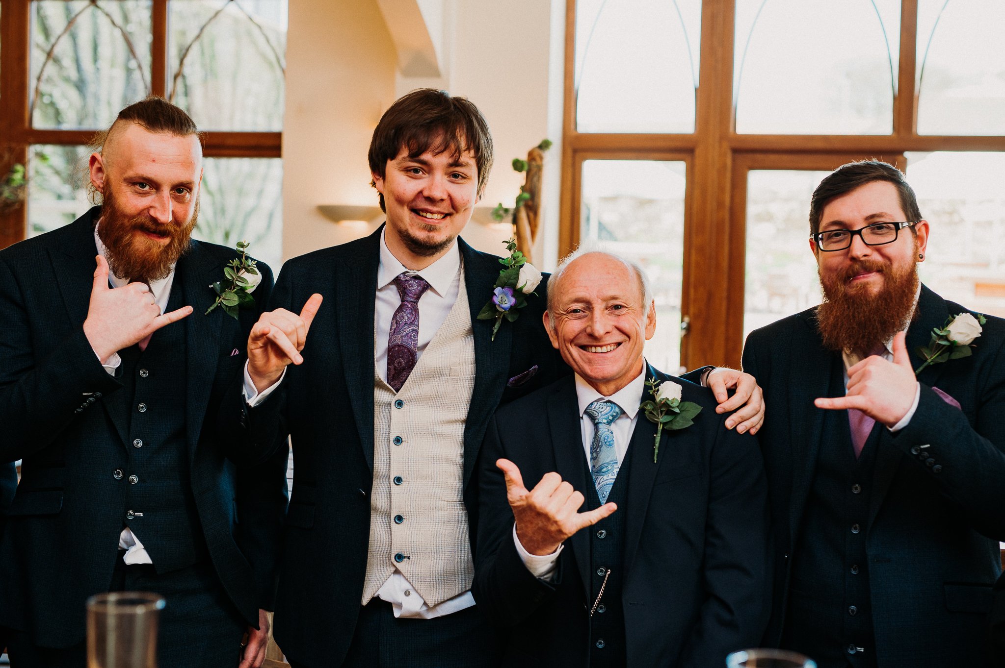 The father of the bride, the groom and some of the groom's party giving a hang ten sign at Sneaton Castle, Whitby.