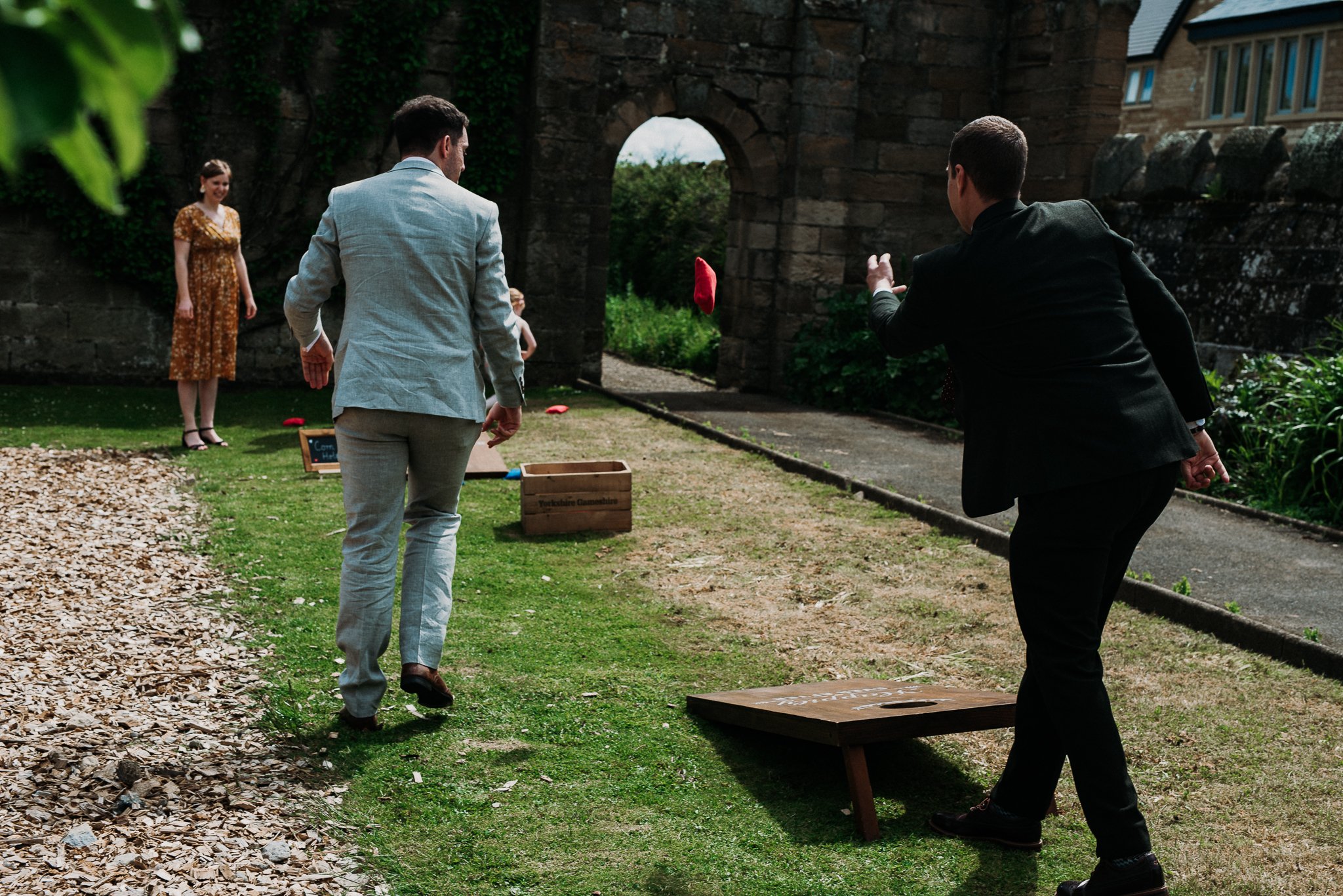 Guests playing corn hole lawn games at the wedding at Sneaton Castle, North Yorkshire.