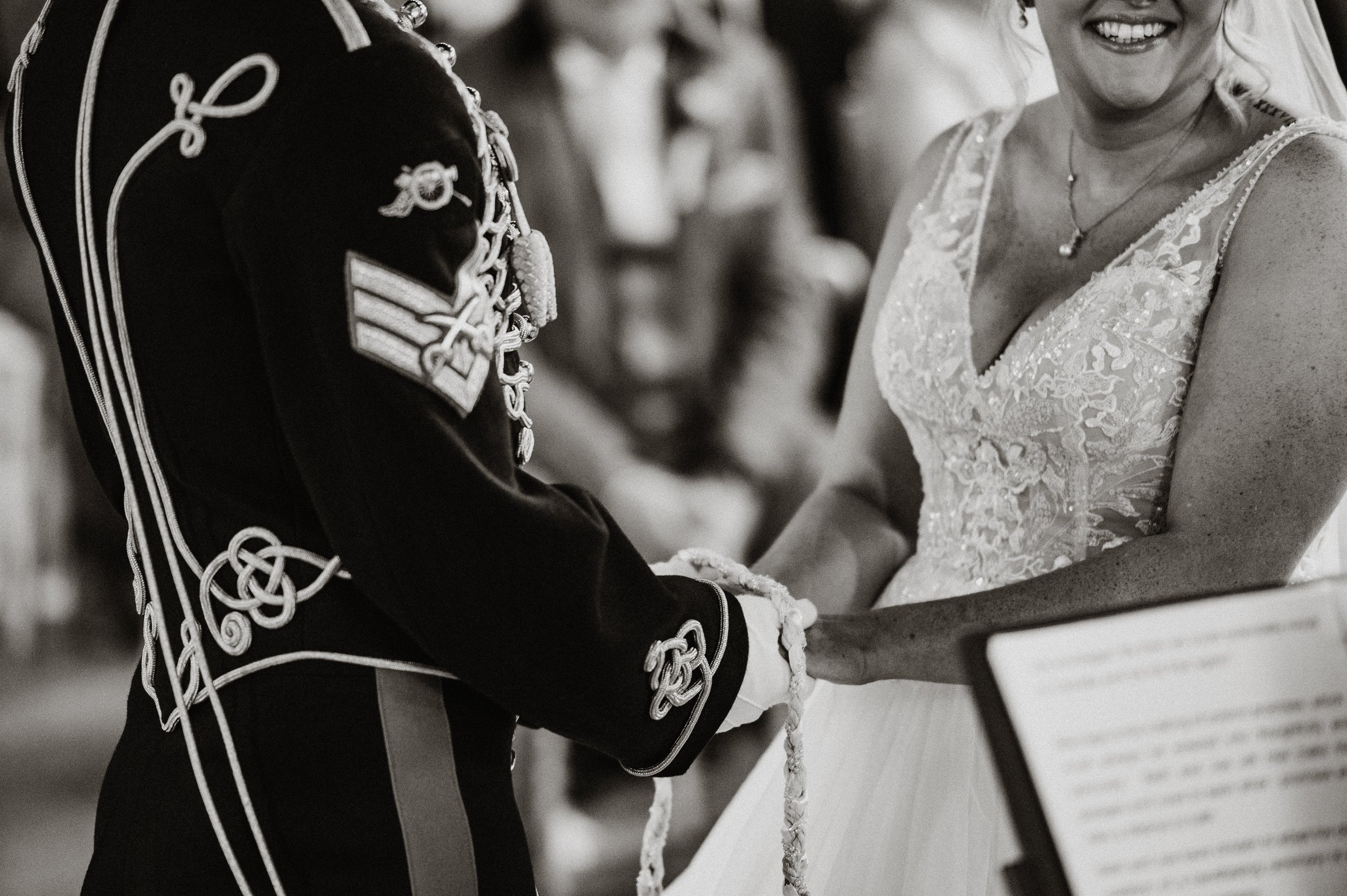 A black and white photo of the hand fasting ceremony that the bride and groom chose to have as part of their celebrant-led celebration at Sneaton Castle, Whitby.