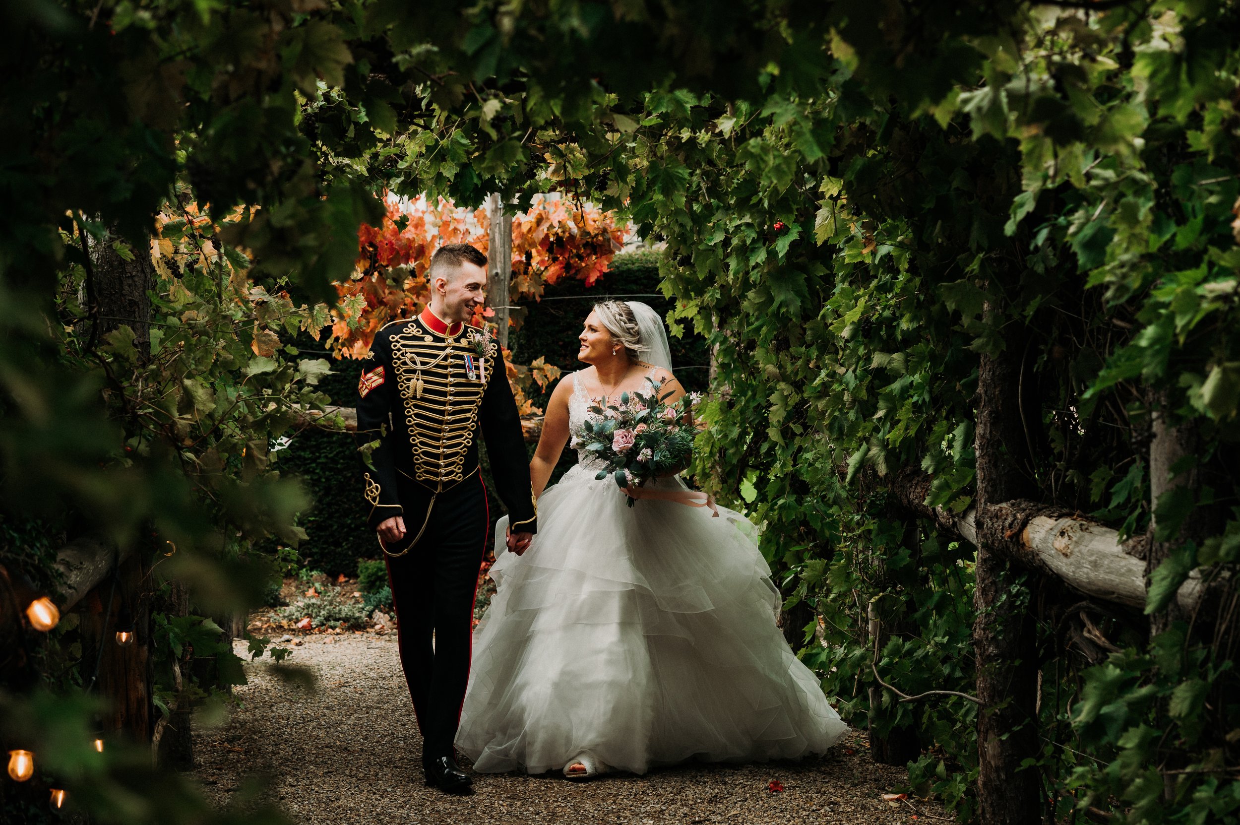 The bride and groom walk through a tunnel of leaves in the gardens at Sneaton Castle, Whitby.