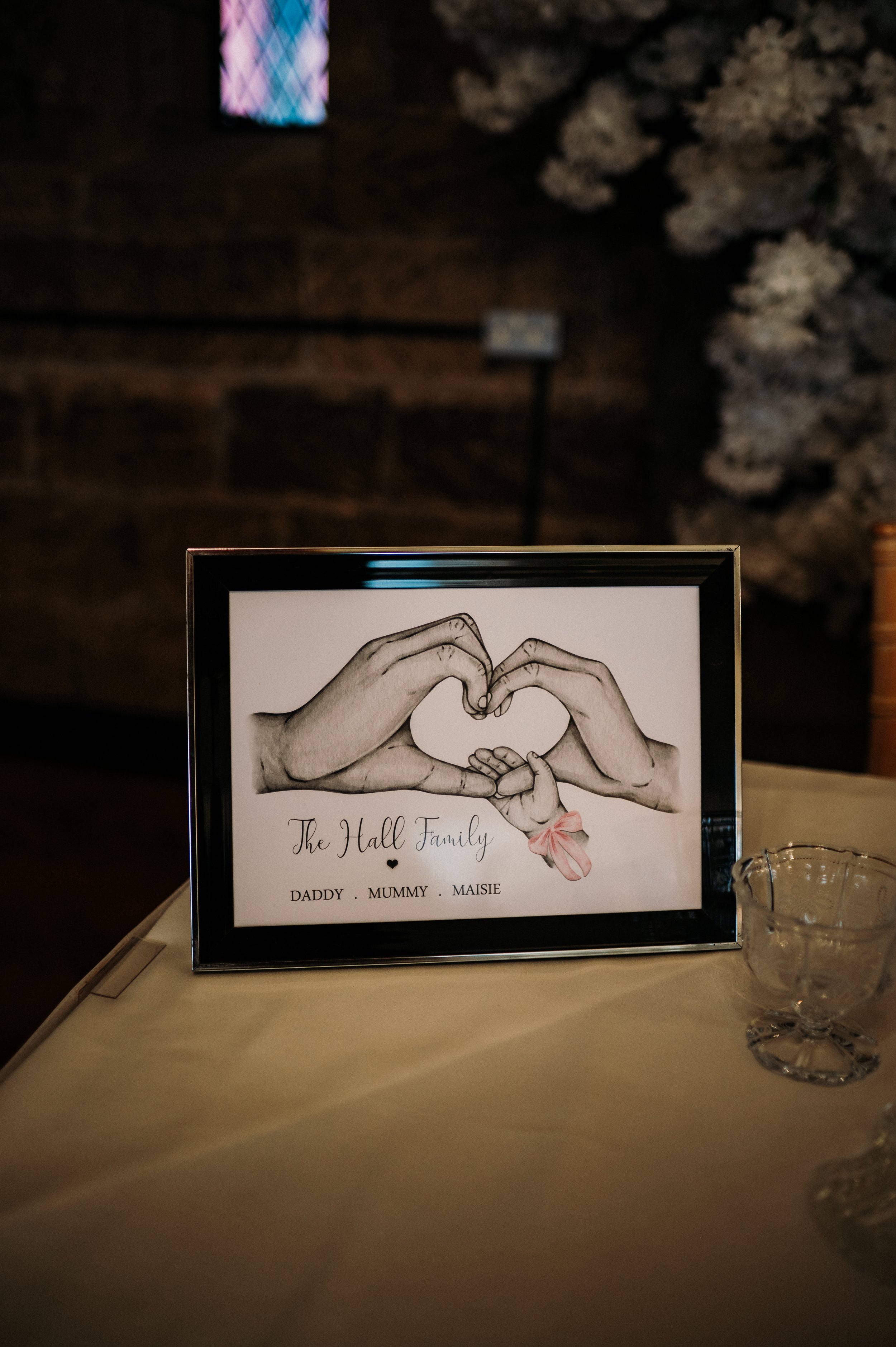A drawn image of the bride's, groom's and their baby daughter's hands together.