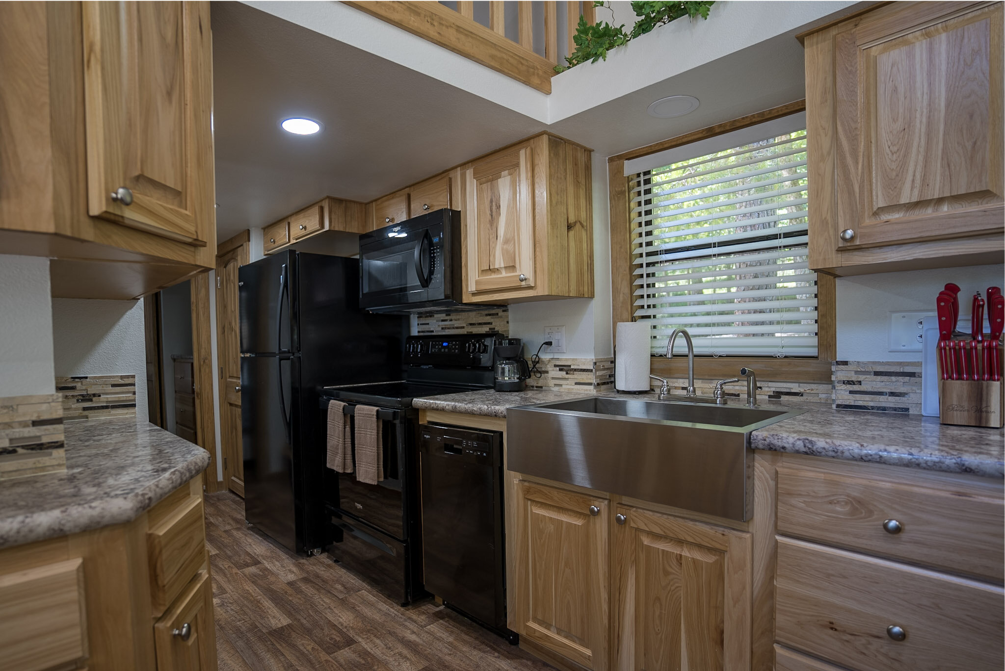 Modern kitchen with wooden cabinets, black appliances, and stainless steel farmhouse sink.
