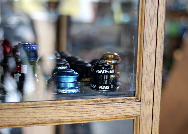 Colorful bicycle bells displayed behind a glass window in a wooden frame.