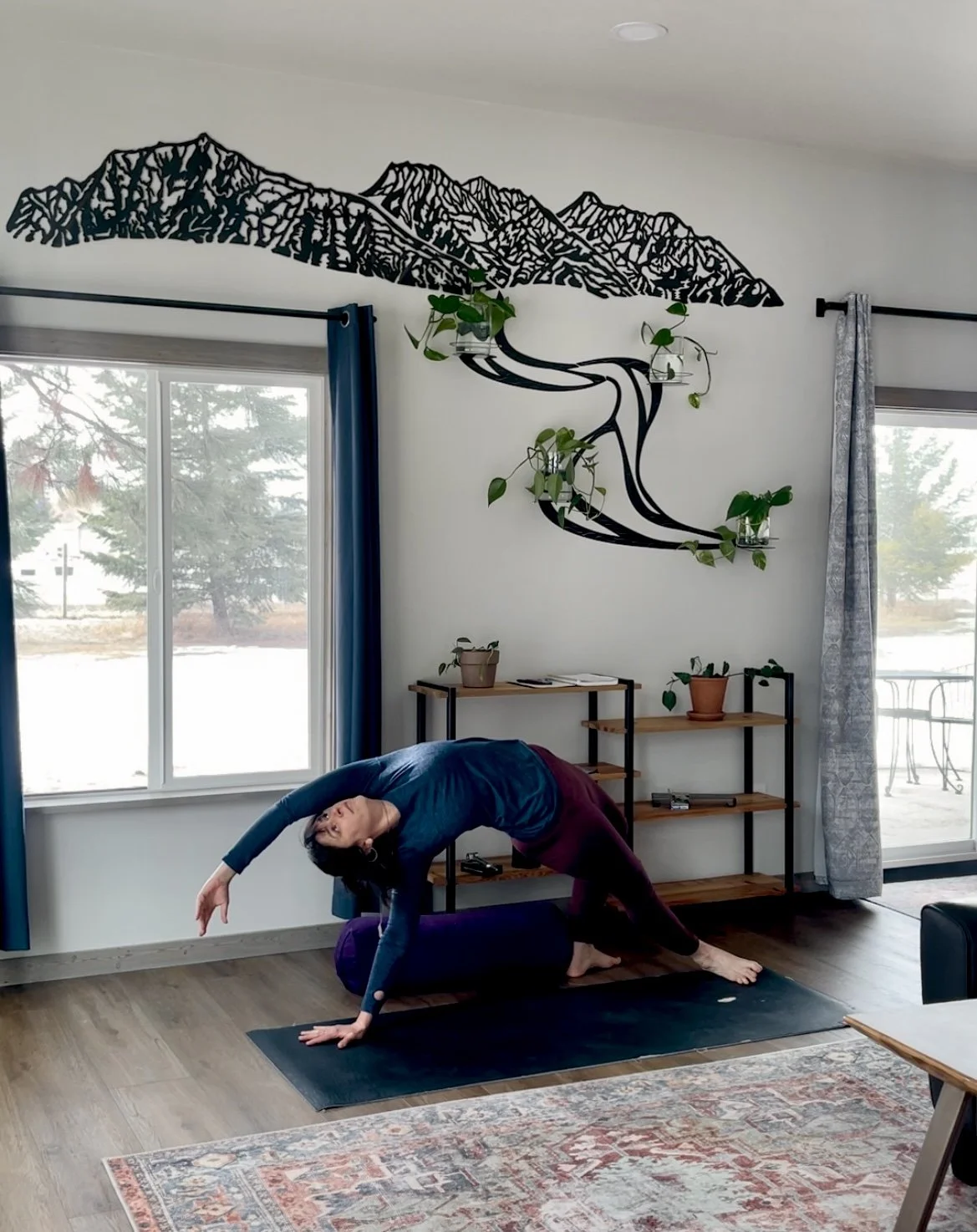Photo of life coach Kelsey Holmes practicing yoga in front of one of her metal art master pieces Glacier Peaks Growing and Flowing by Creative Combinations Montana in Inspiration Cabin.
