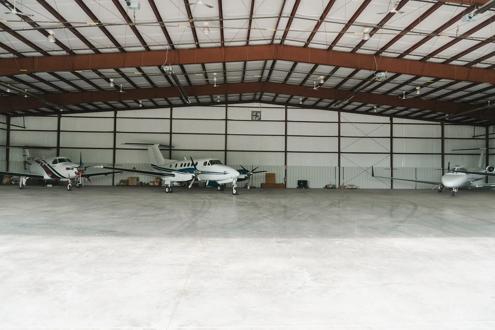 Interior of an aircraft hangar with four small airplanes parked inside.