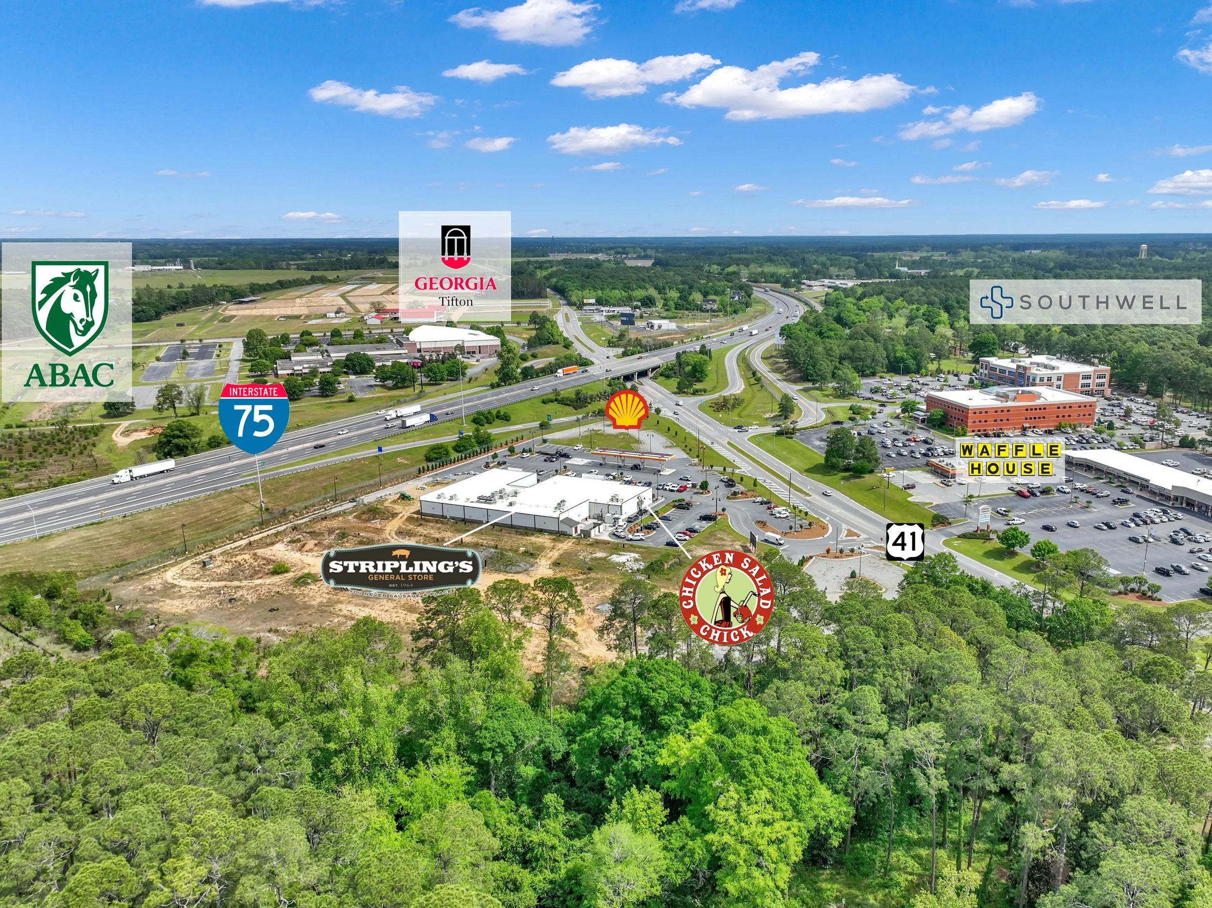 An aerial view of a commercial area near highways, featuring signs for ABAC, Georgia Tifton, Shell gas station, Waffle House, Southwell, Stripling's General Store, chicken salad Chick, and US Highway 41, surrounded by trees and greenery.