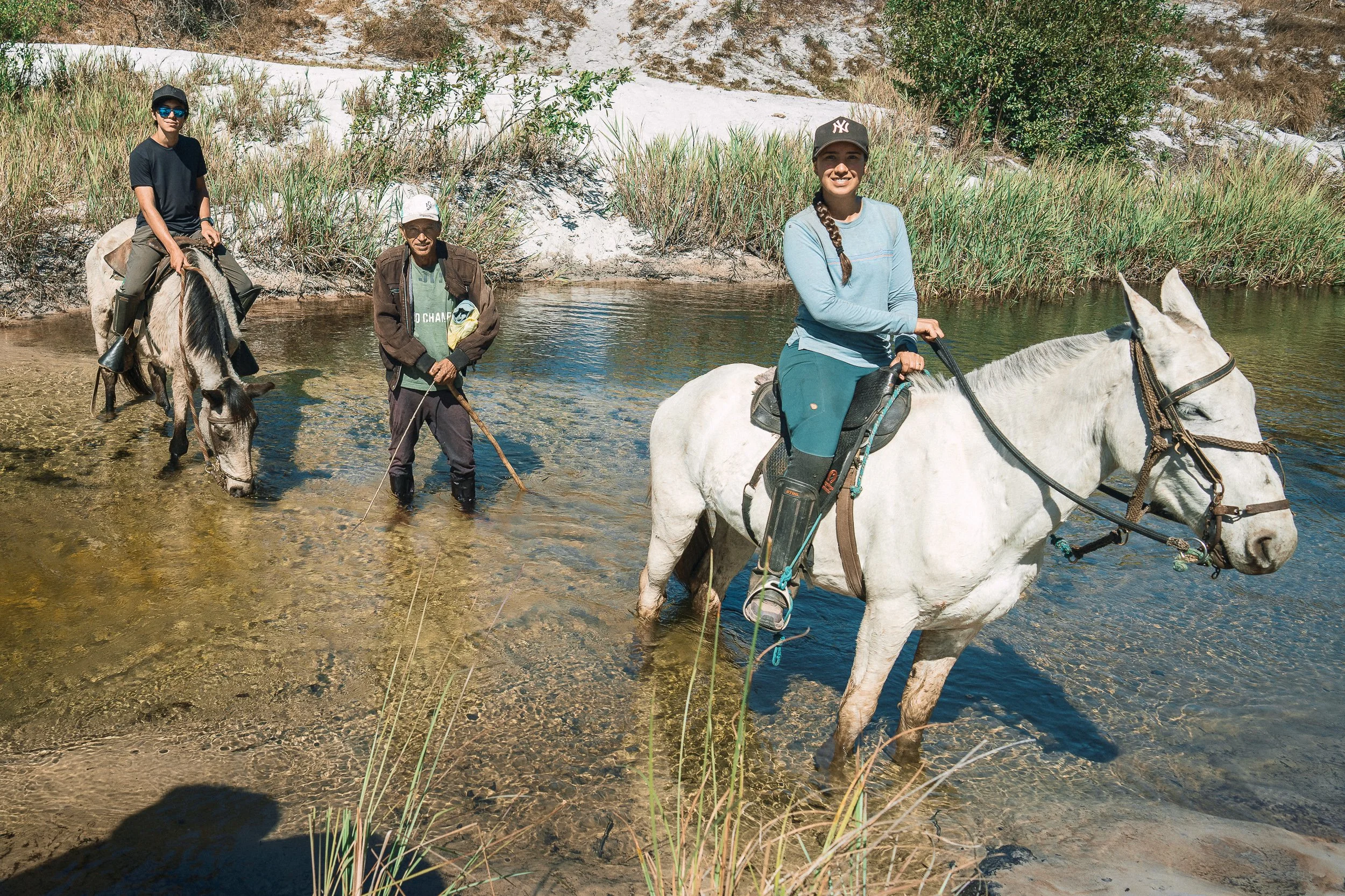 Tiago and Elisa crossing a river on horseback during a field trip with Dorico in the Vale do Rio Preto, Sempre Vivas National Park