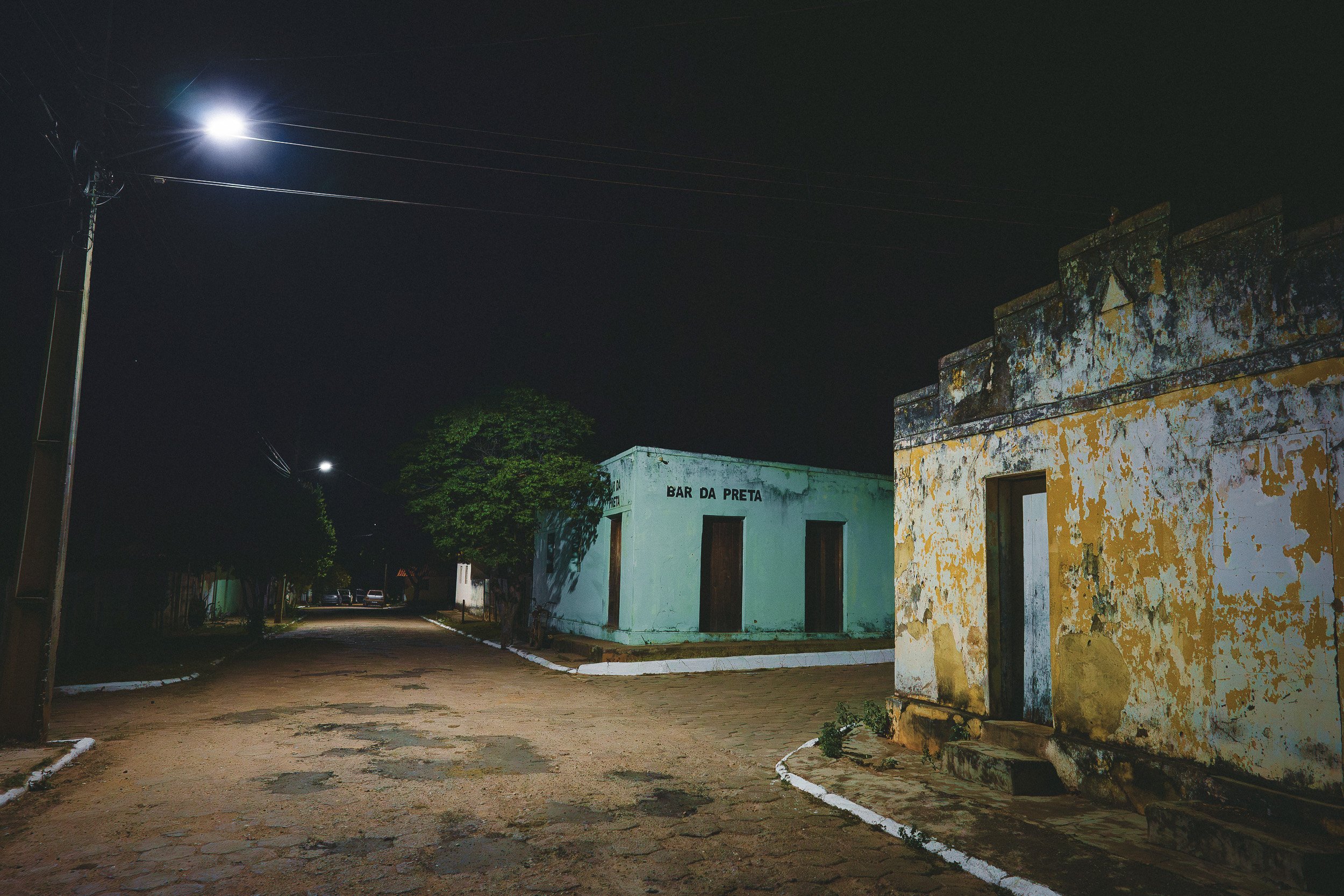 A quiet street in Curimataí after the 7 de Setembro festivities, with the Bar da Preta and weathered buildings under streetlights.