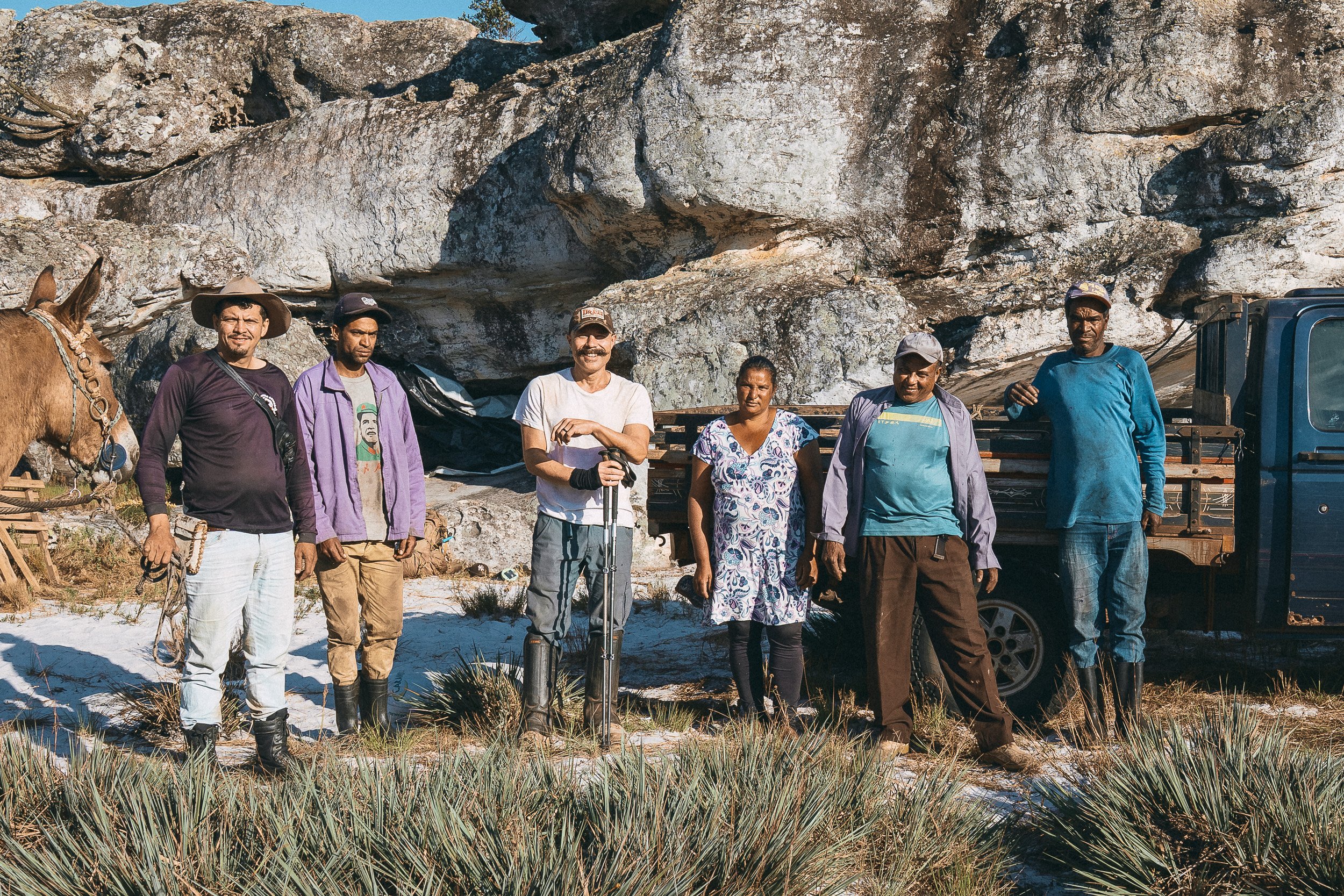 Guim, Ronaldo, Eddie, Silvia, Leandro, and Gonçalo pose beside Baiana and an old pickup truck in front of Leandro's rock shelter in Sempre Vivas National Park