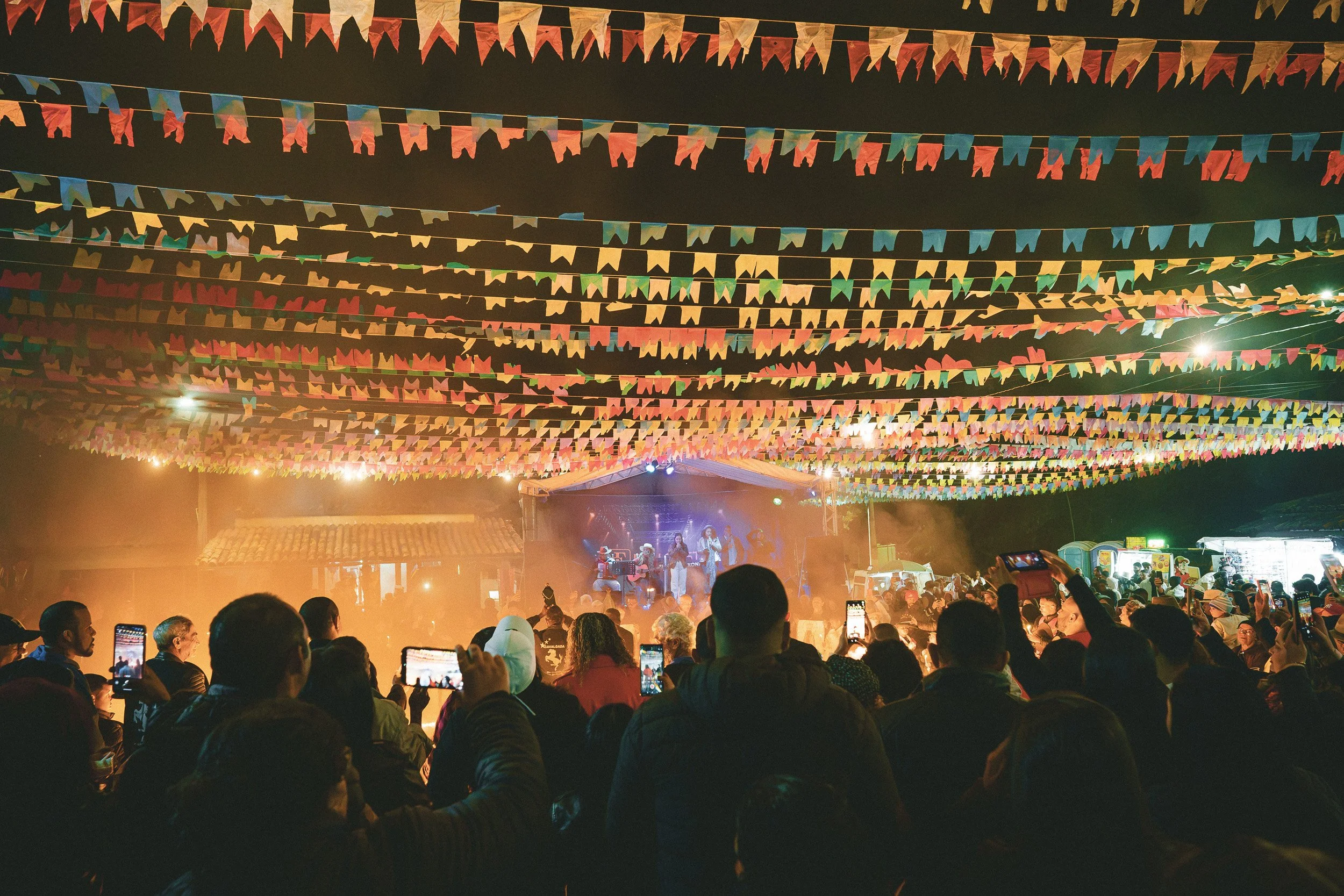 A country band plays to a large crowd in the street at night in downtown São Gonçalo do Rio das Pedras, Minas Gerais