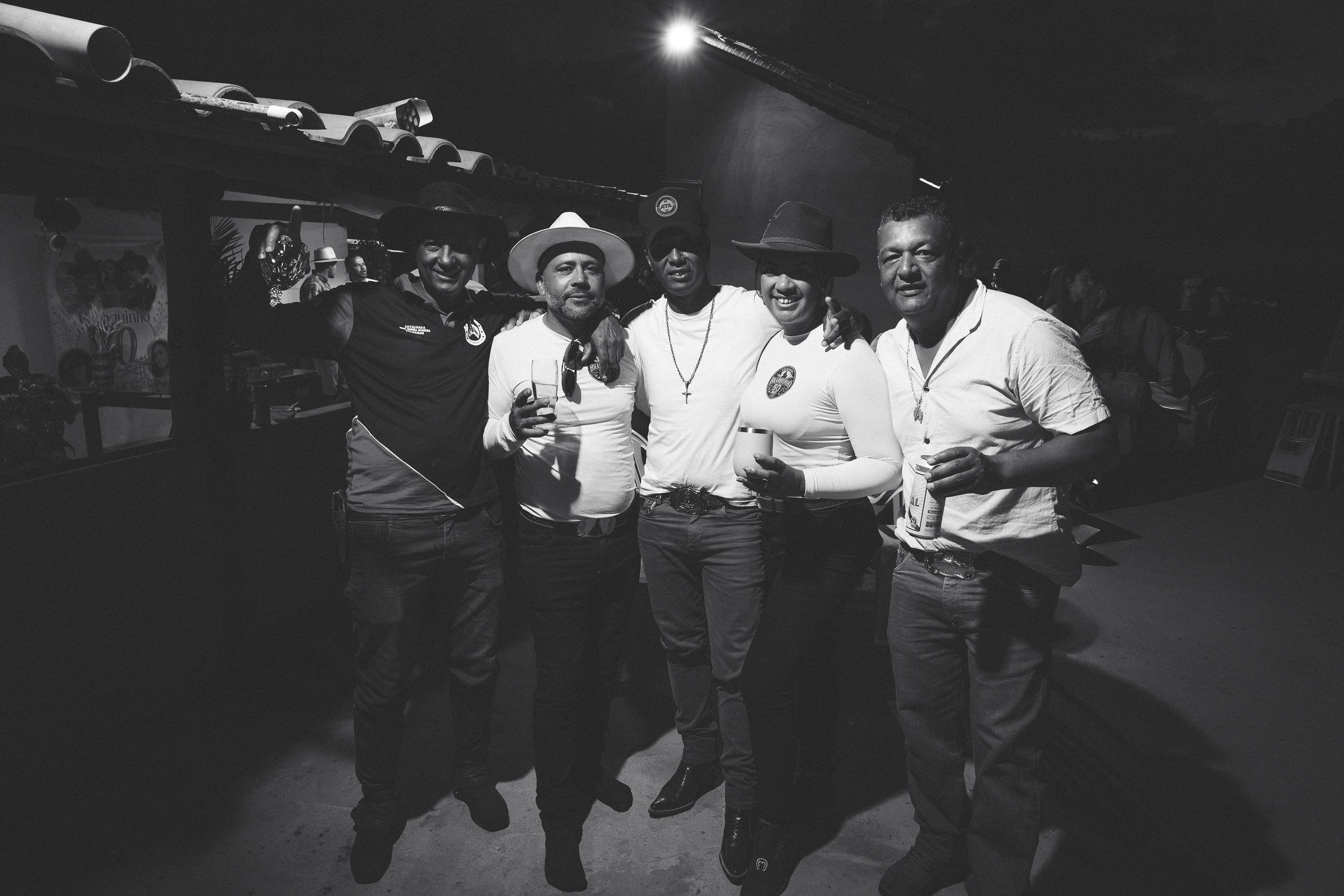 Branquinho and Ana Claúdia pose with friends and drinks in a black-and-white photograph at his 50th birthday party near Guinda, Diamantina.
