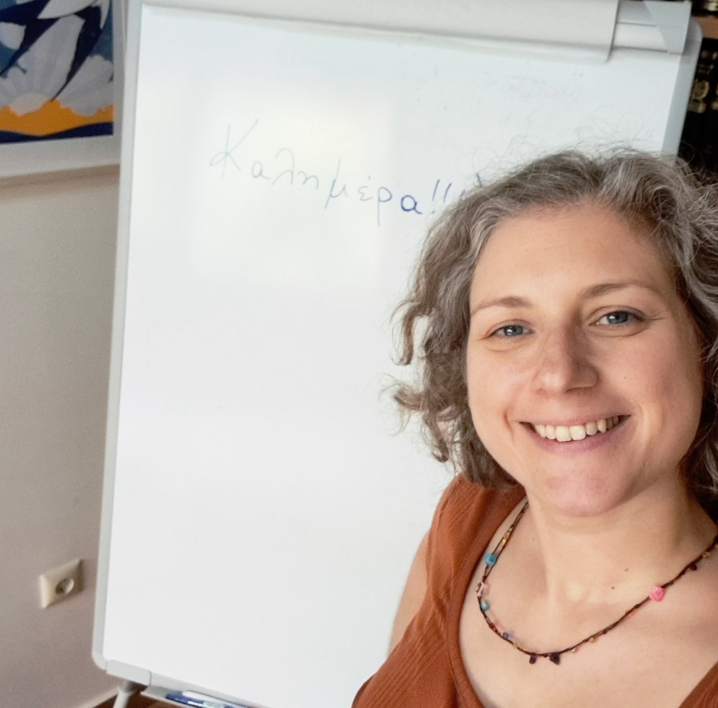 Greek teacher Danae Florou smiling in front of white board