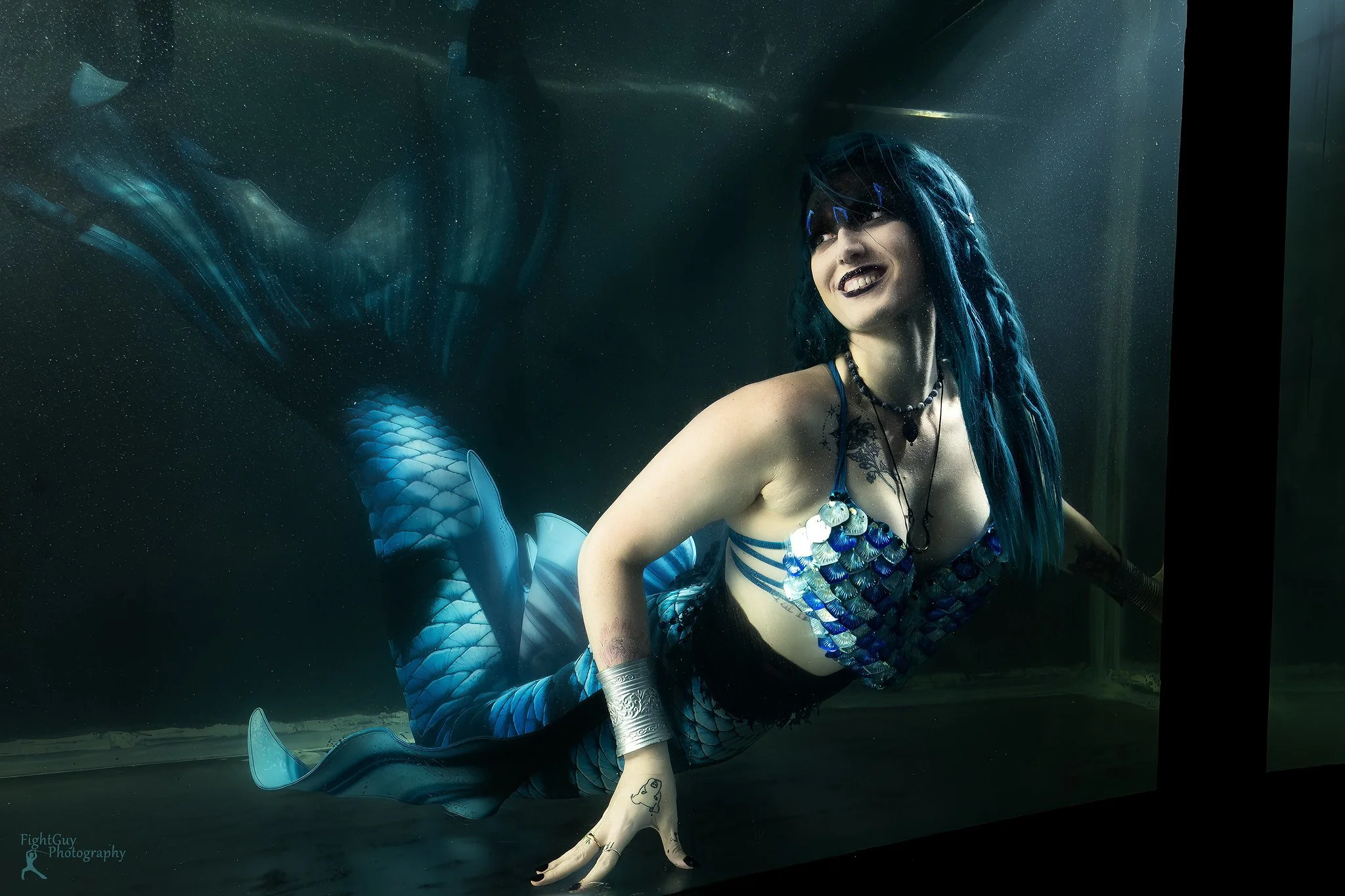 A blue and black themed mermaid swimming in a 1000 gallon mermaid tank.