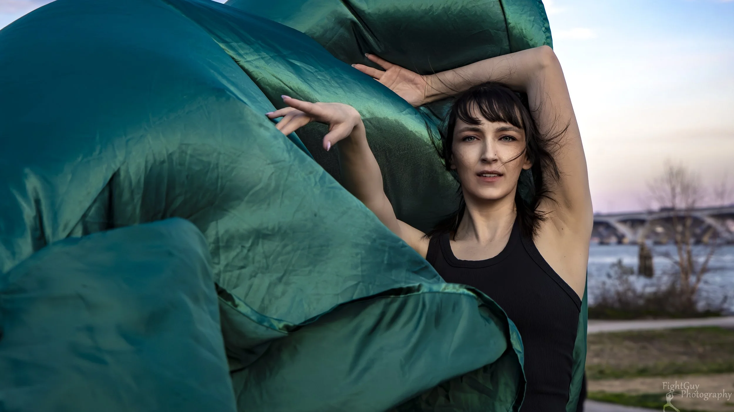 A dancer in a black tank top, in Old Town Alexandria, poses with billowing green fabric