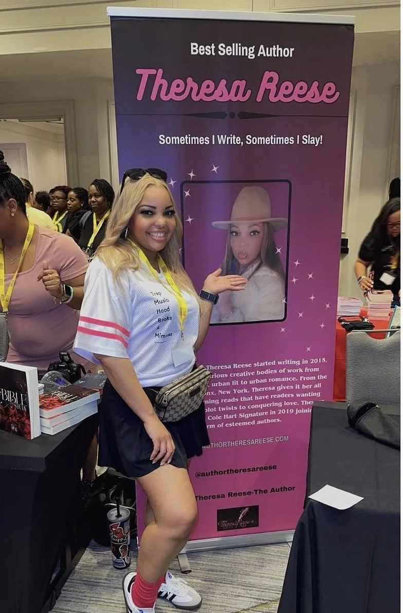 A woman with blonde hair posing in front of a purple and pink promotional banner for Theresa Reese, a best-selling author. She is smiling and wearing a sport jersey, a fanny pack, sneakers, and red socks.