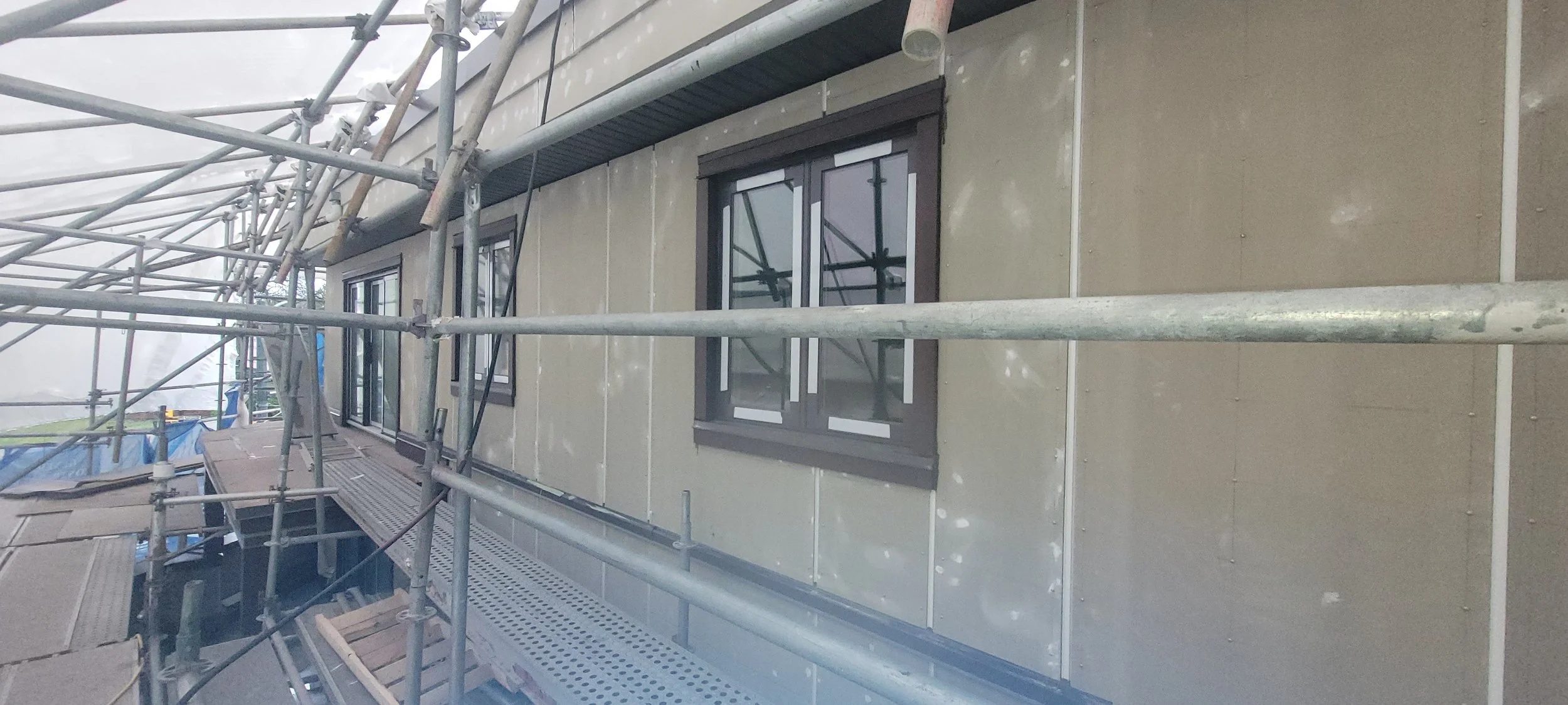 Exterior of a building under construction with scaffolding and windows.