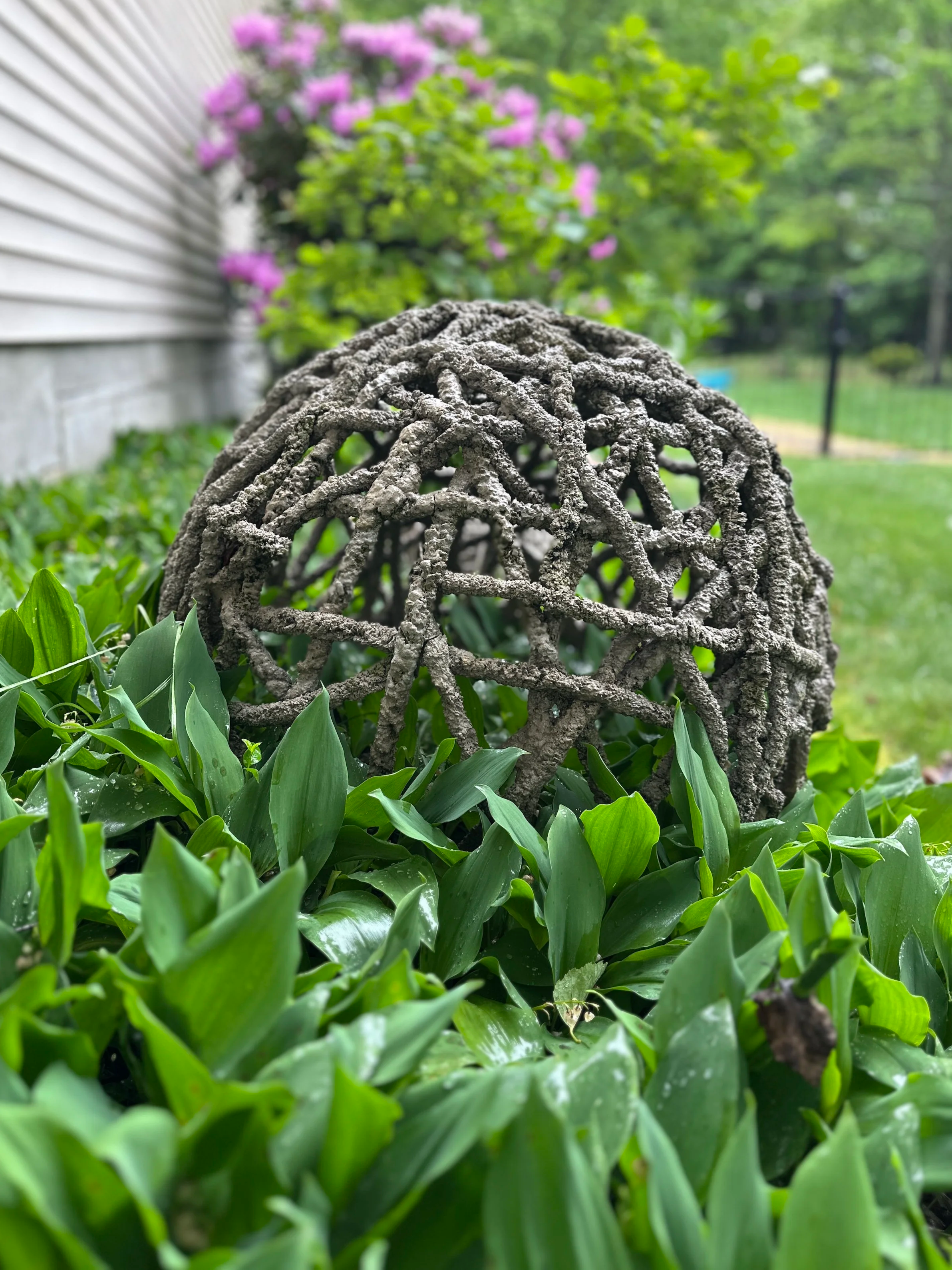 Large string sphere sitting among a bed of Lily of the Valley's.  