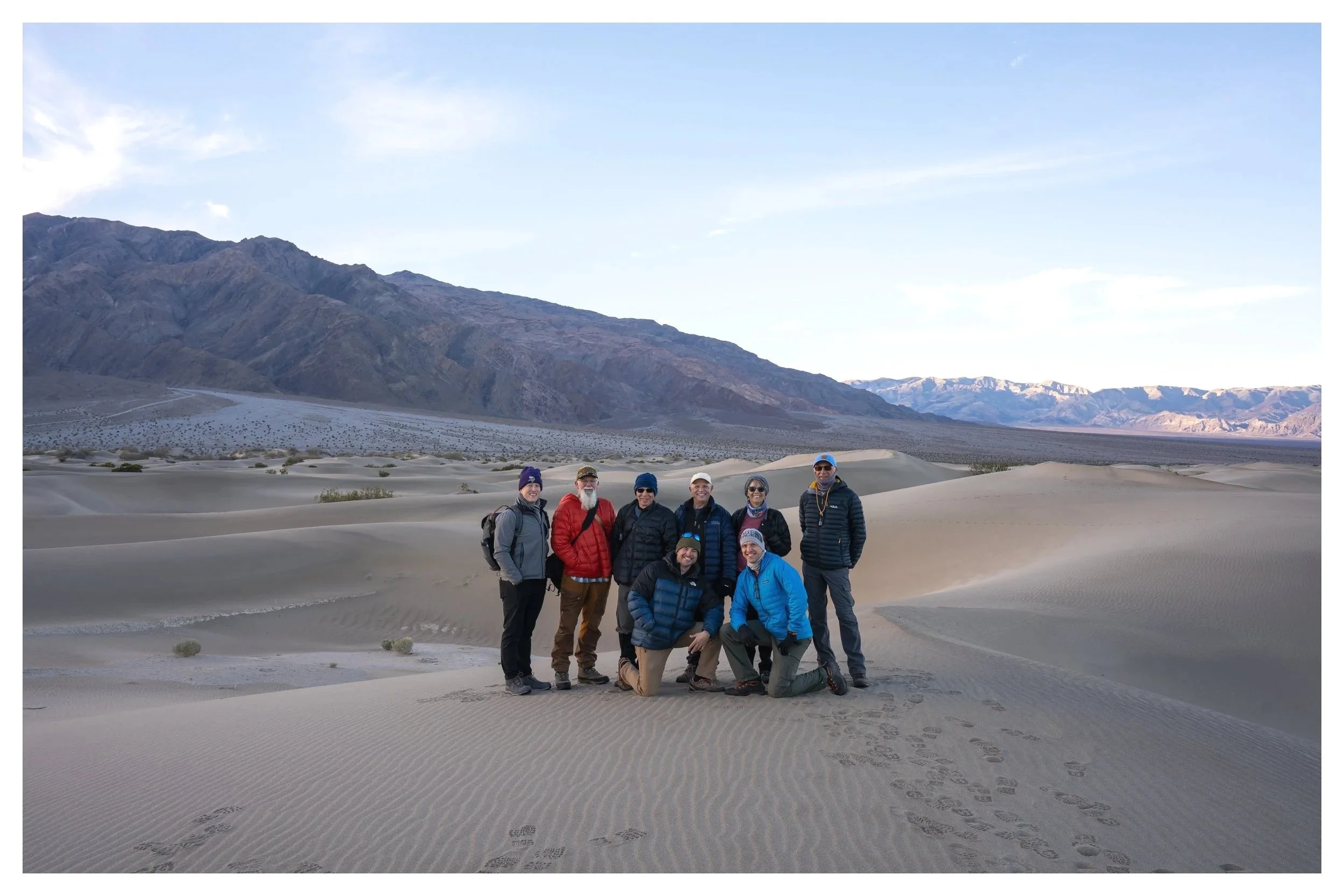 A group of photographers standing on a sand dune in Mesquite Dunes in Death Valley National Park during a workshop with Andrew Hertel