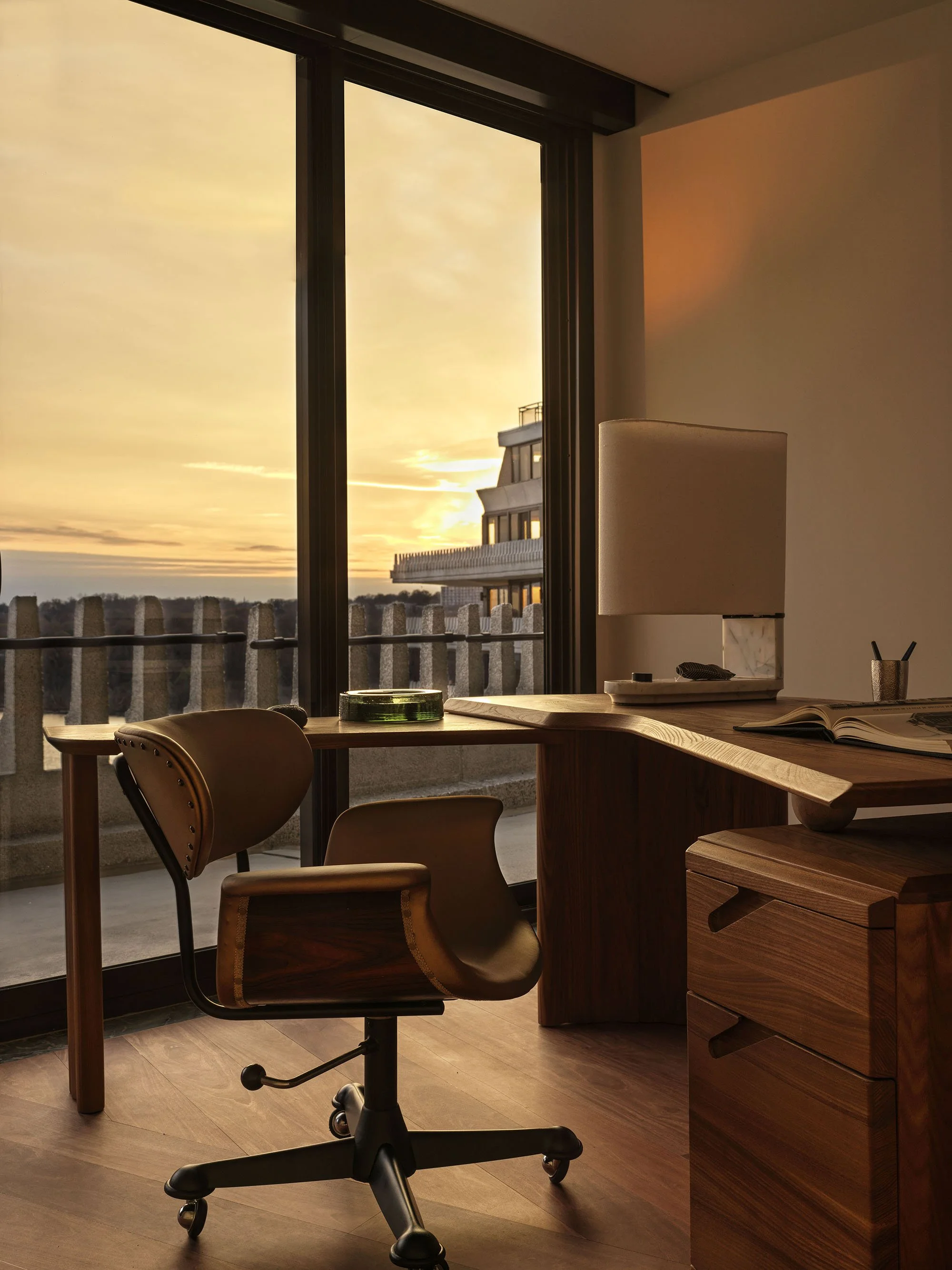 A home office with a vintage desk and chair overlooking the Potomac River at sunset
