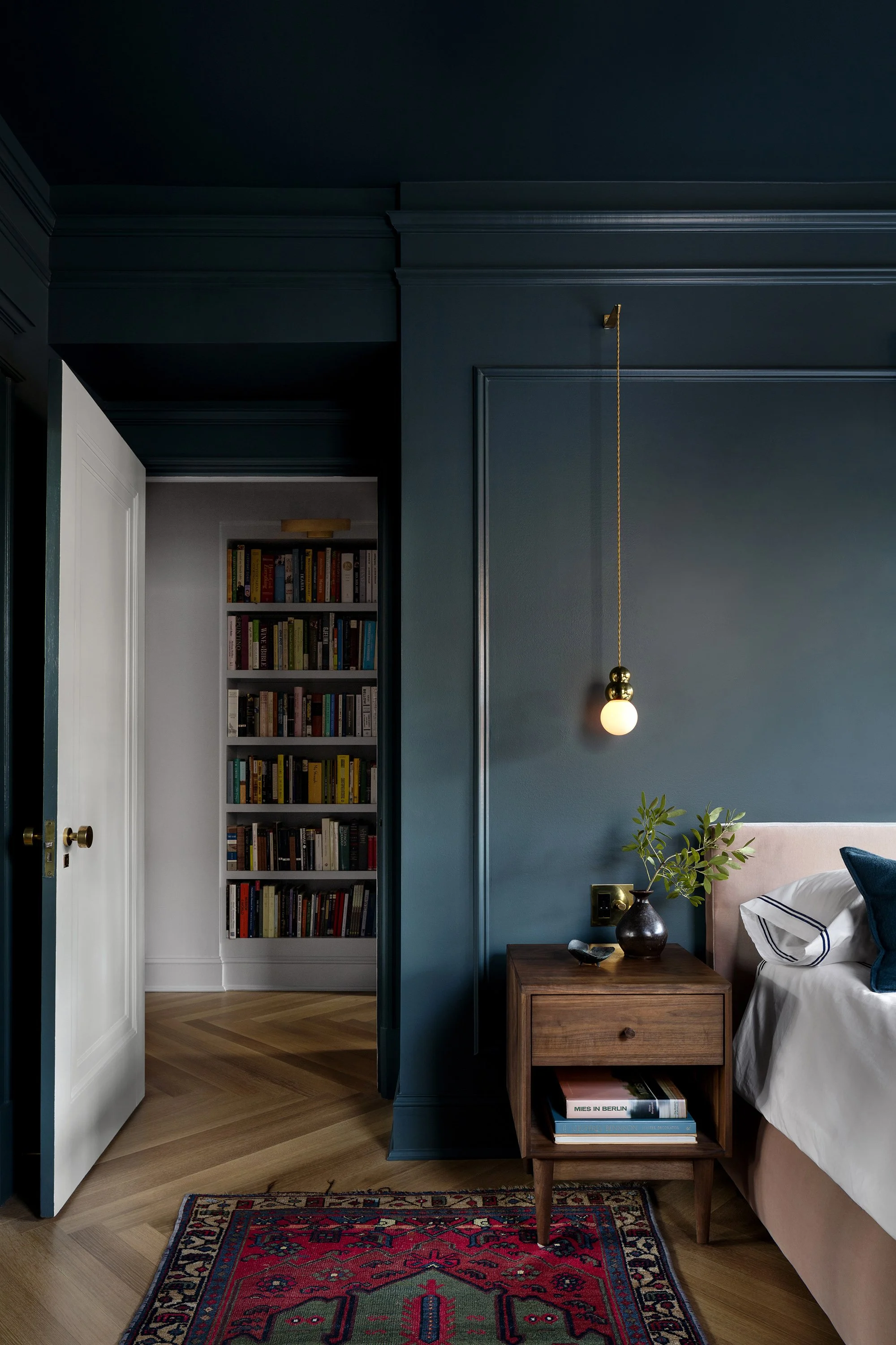 A deep teal color drenched bedroom in an apartment designed by architect Nicholas Potts