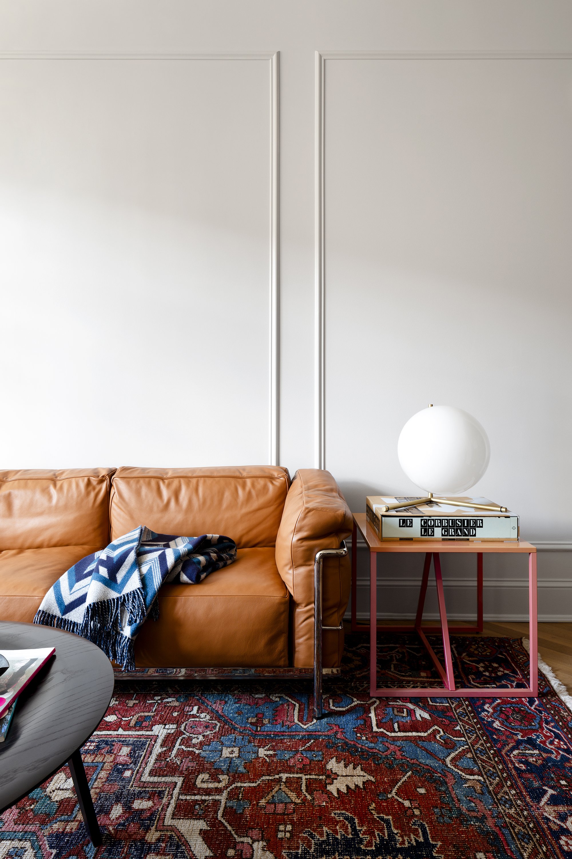 A Le Corbusier sofa, an antique carpet, and a pink table in an apartment designed by architect Nicholas Potts