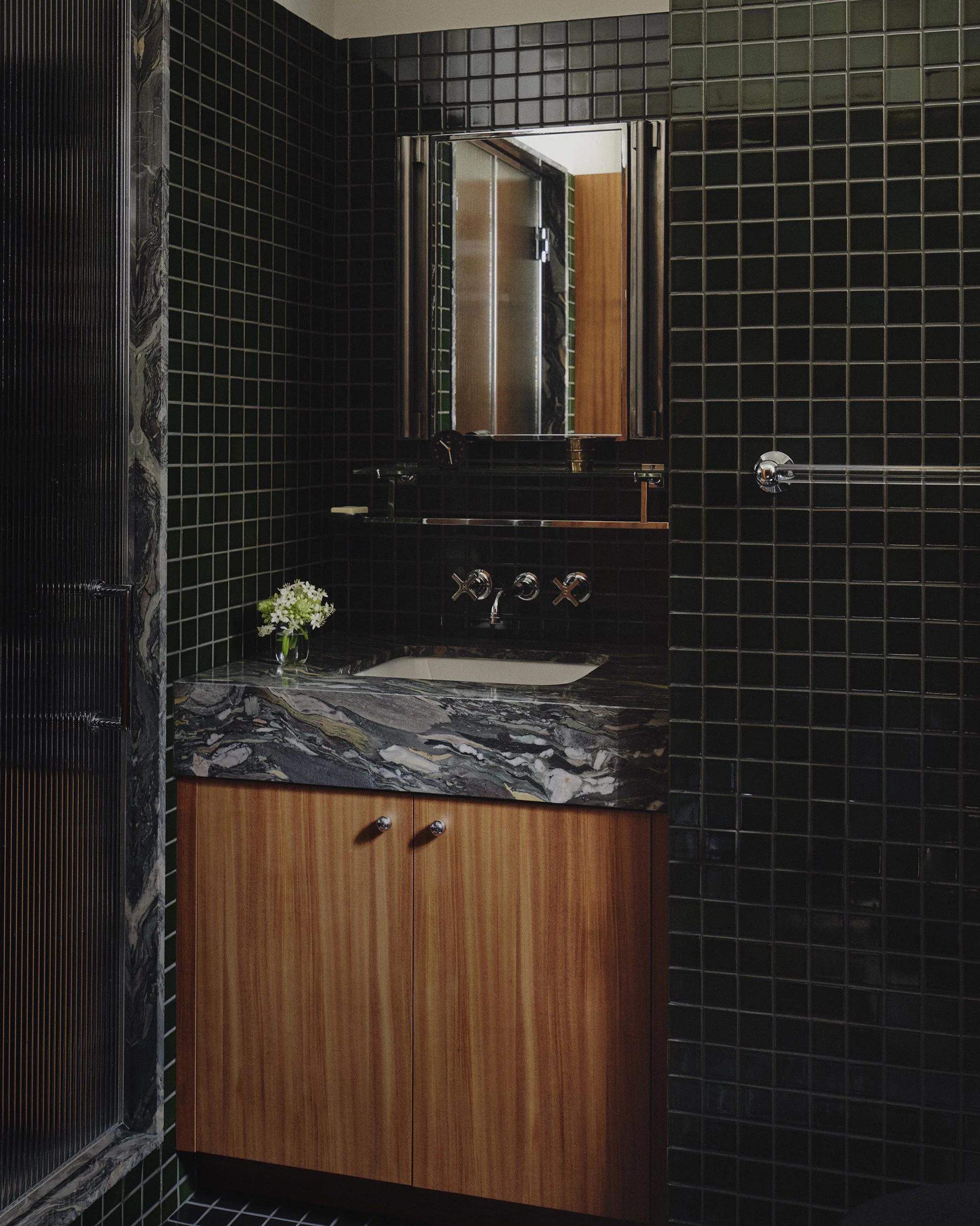 A bathroom in the Rockefeller Apartments with a dark green Heath Ceramics tile and a marble vanity