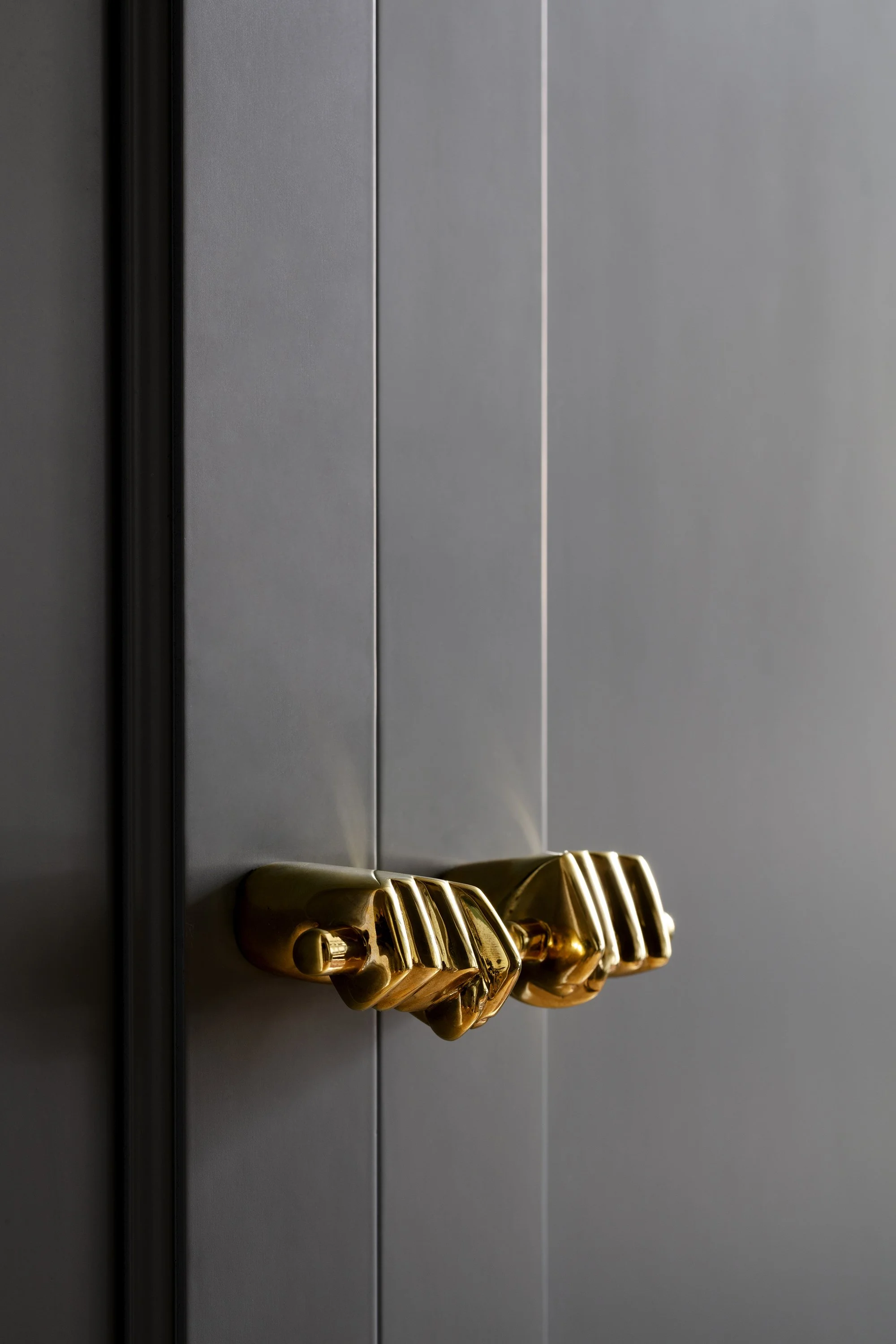 A detail shot of fist-shaped brass cabinet pulls in an apartment designed by architect Nicholas Potts