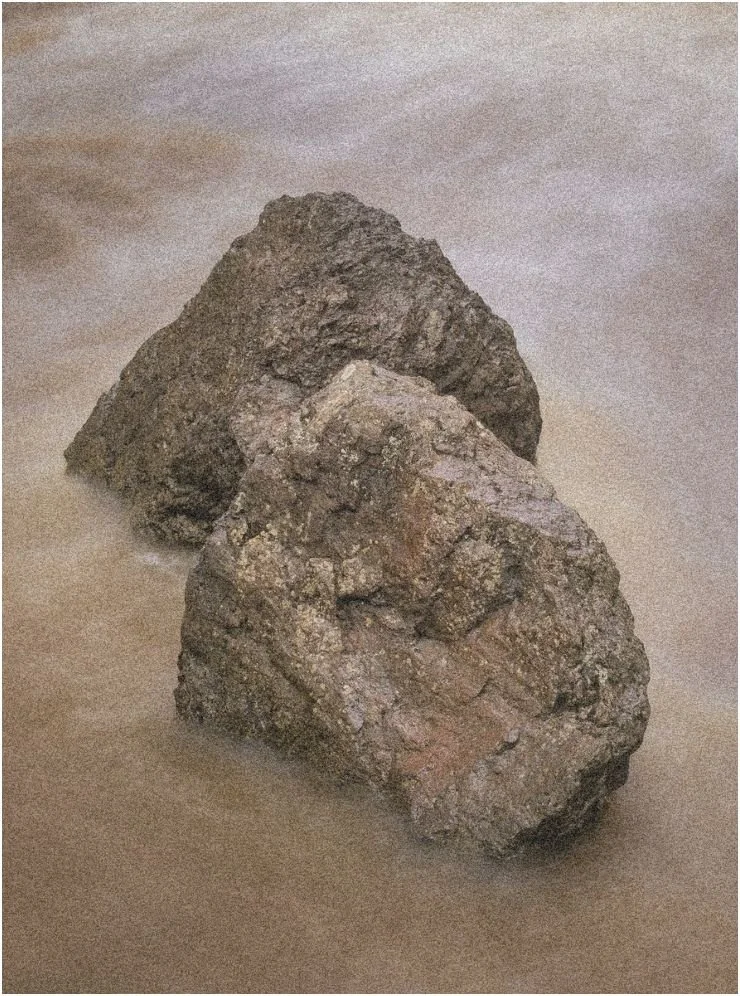 Two rocks partially submerged in shallow water.
