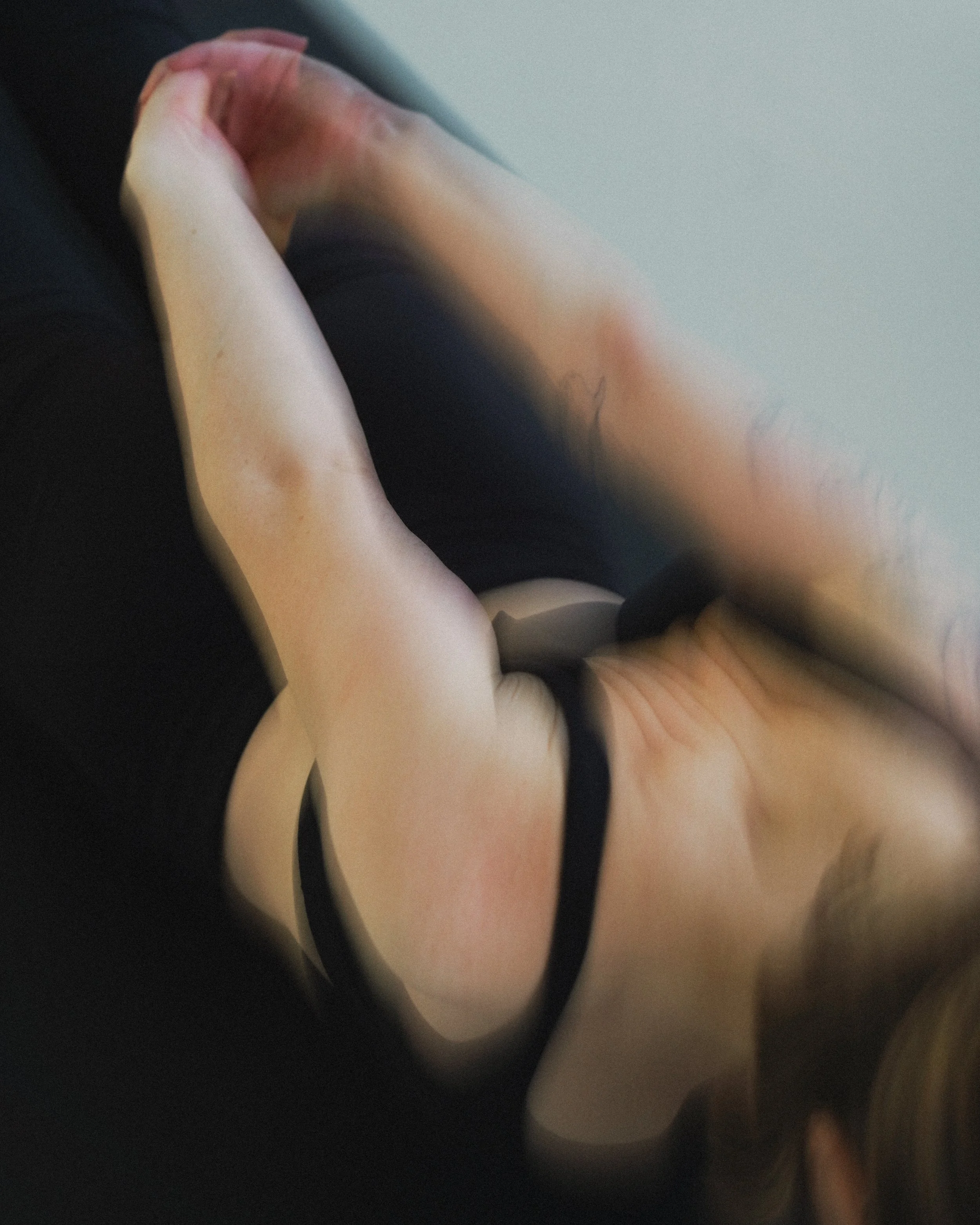Person laying on stomach with interlaced fingers behind low back moving through Locust Yoga Pose in yoga studio in London. 