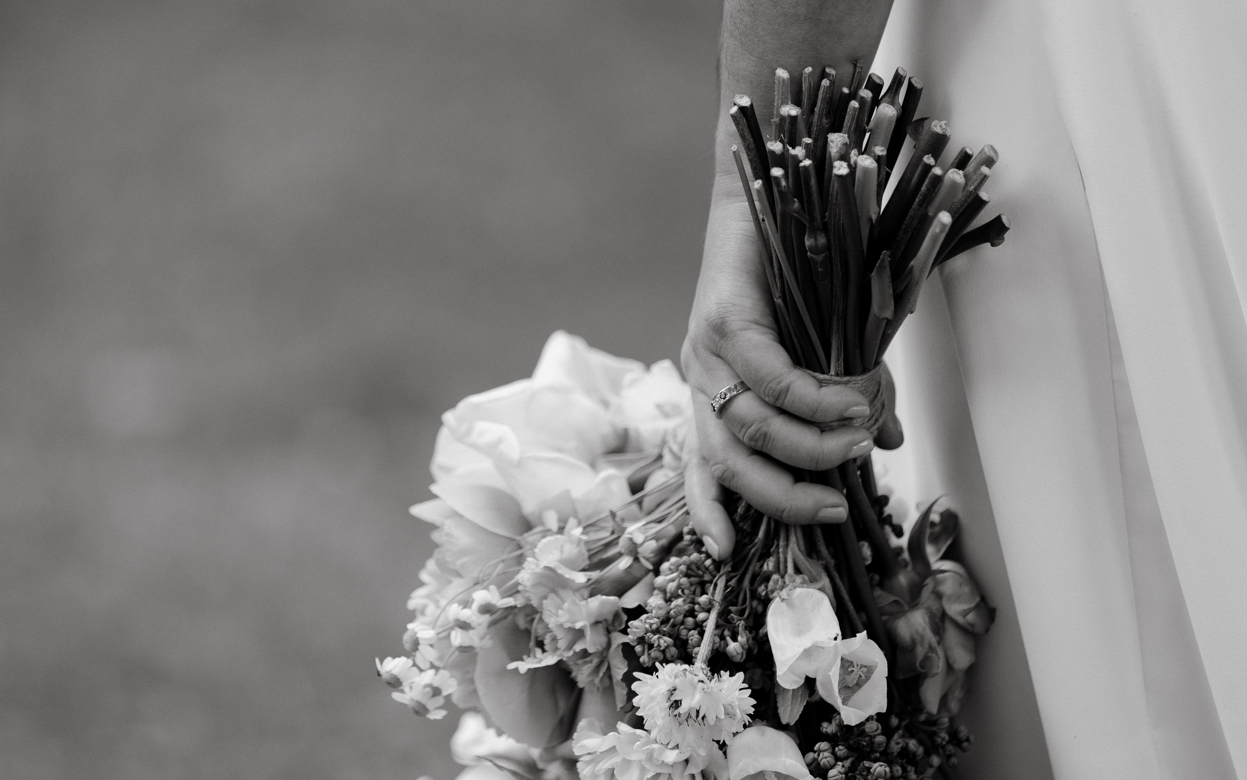 A woman holding a bouquet of flowers in her hand, close-up shot in black and white.