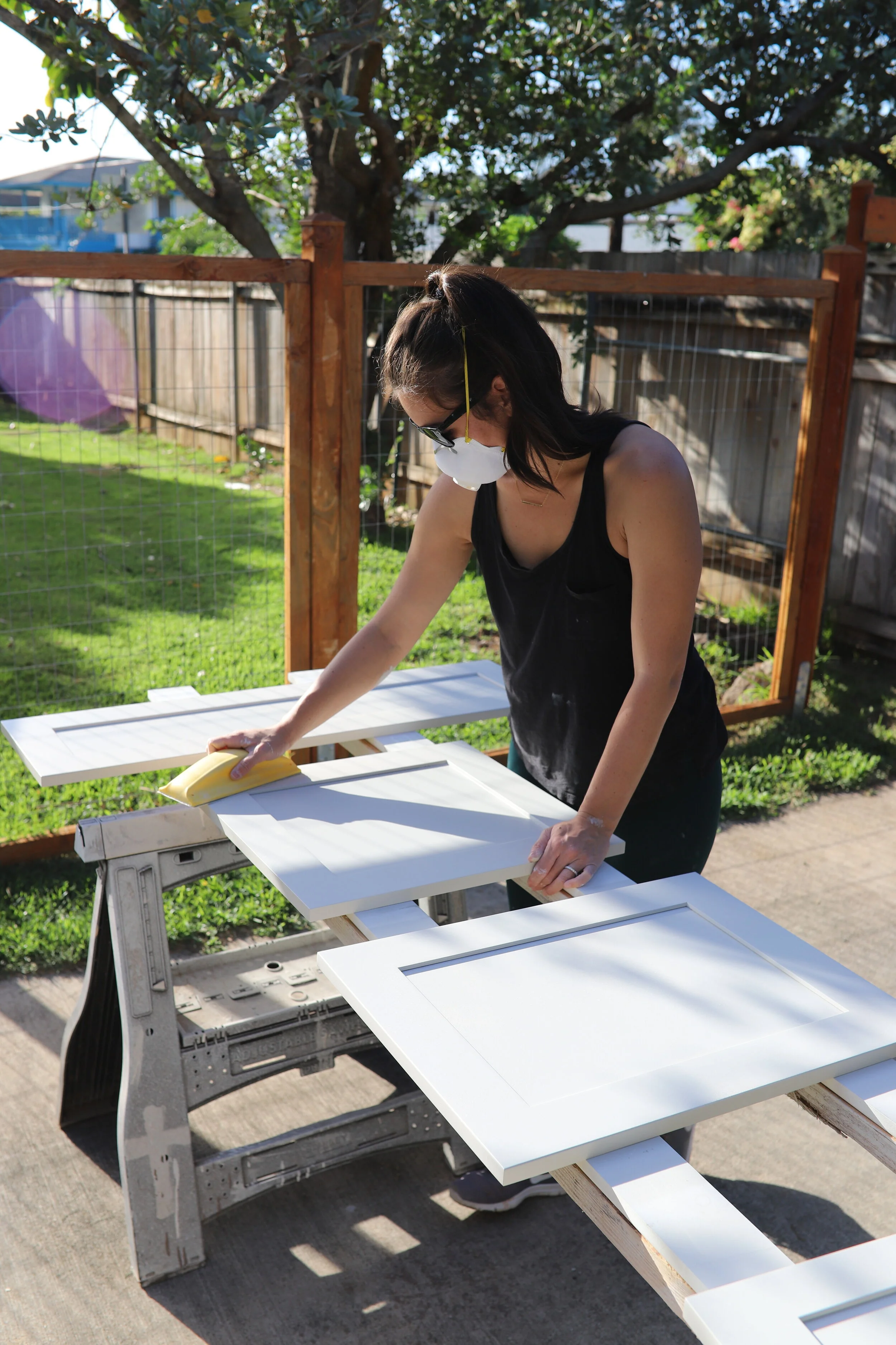 woman sanding kitchen cabinet