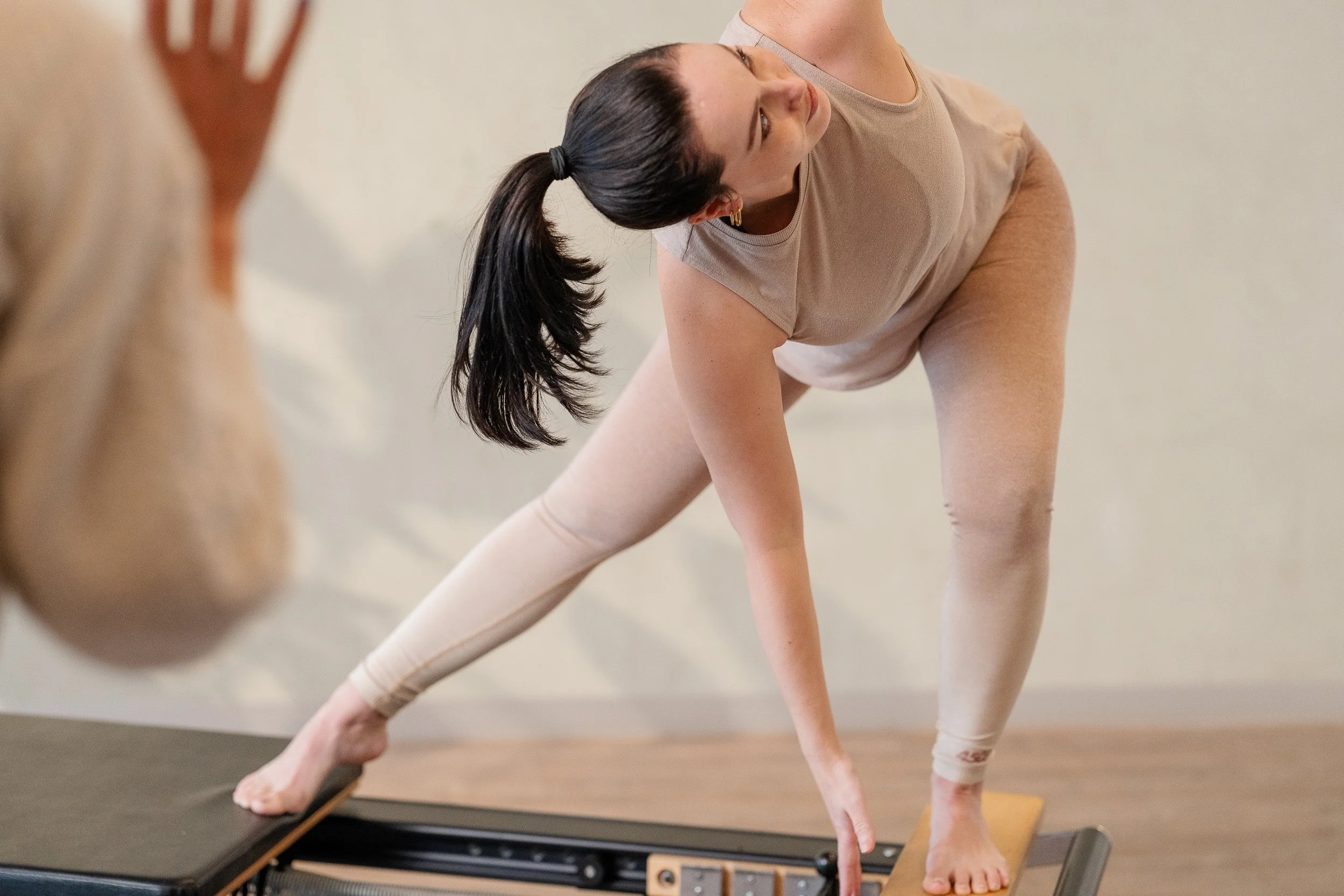 A woman practicing pilates on a reformer machine in a studio.