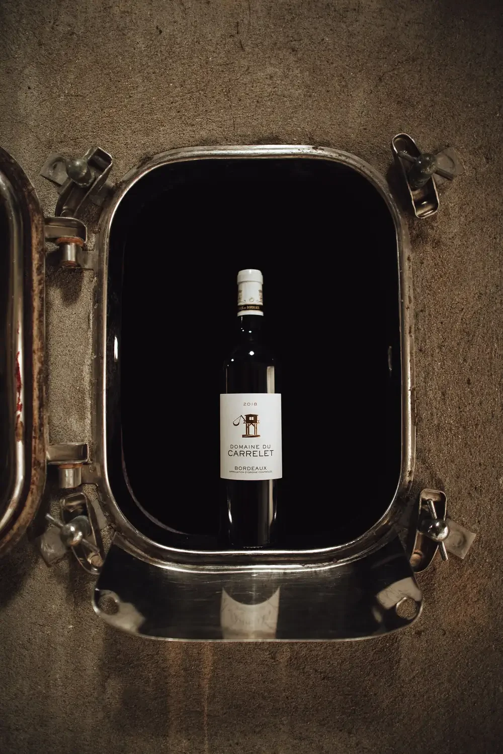 Bouteille de vin du Domaine du Carrelet présentée dans une cuve du chai à Saillans.