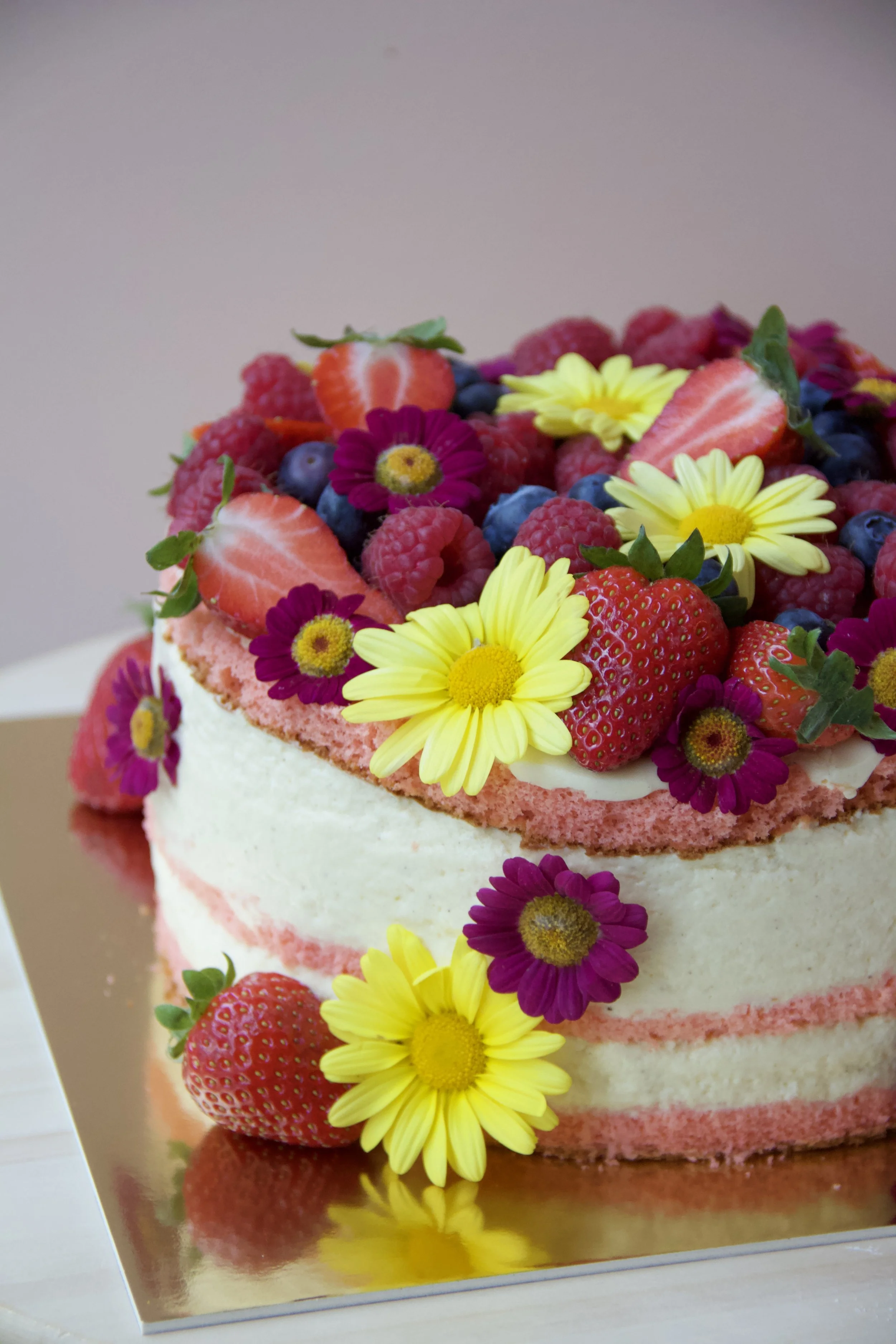 Naked cake with fresh berries and edible flowers