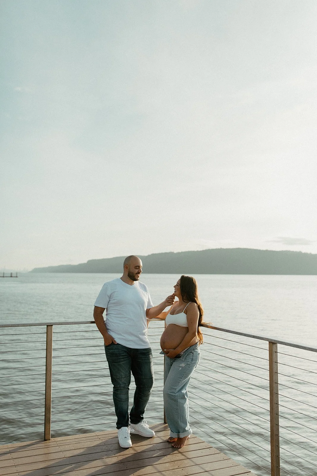 A couple pose for maternity photos during sunset on the water in Dobbs Ferry NY