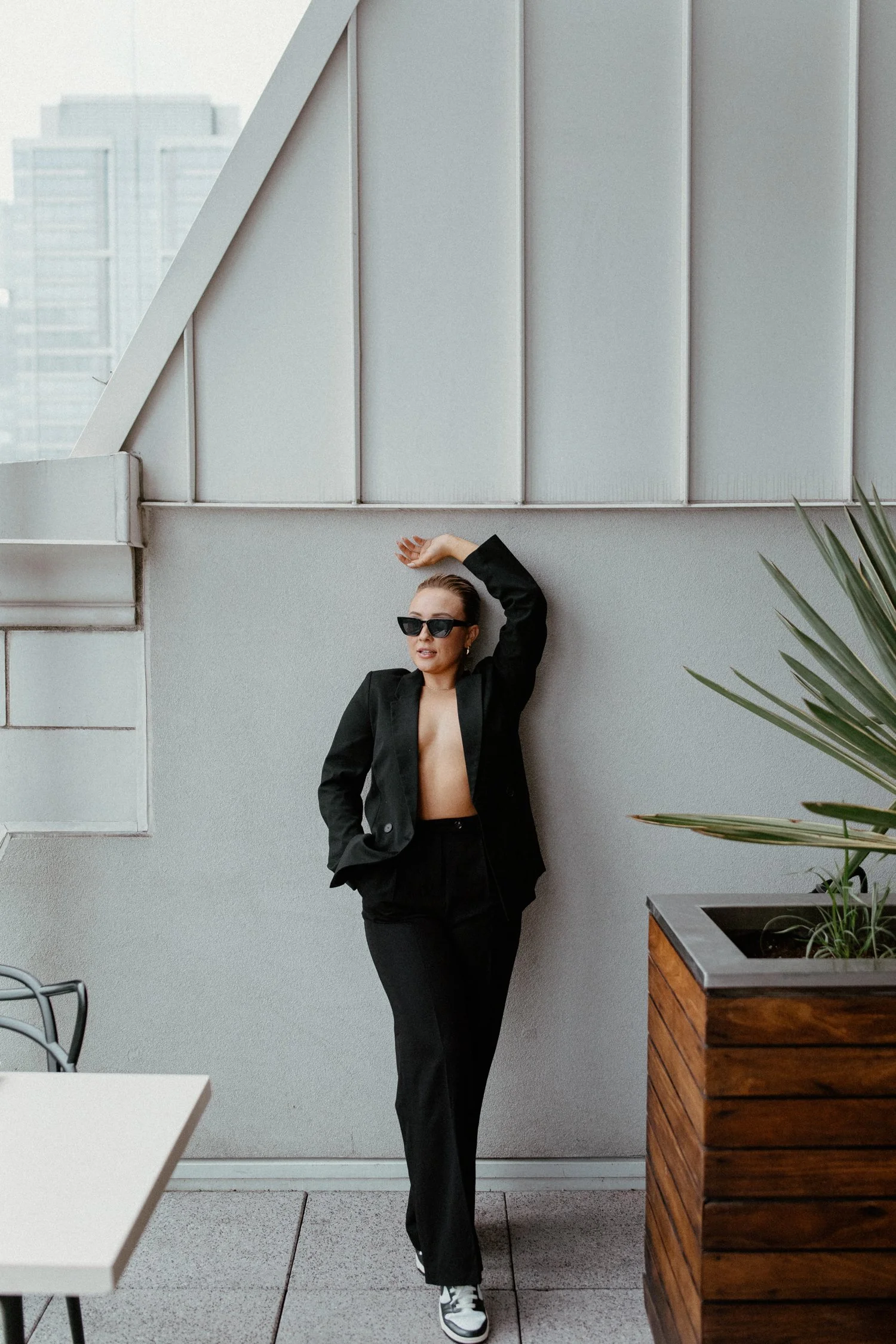 A woman dressed in all black, including Nike sneakers poses on a rooftop bar in Oregon