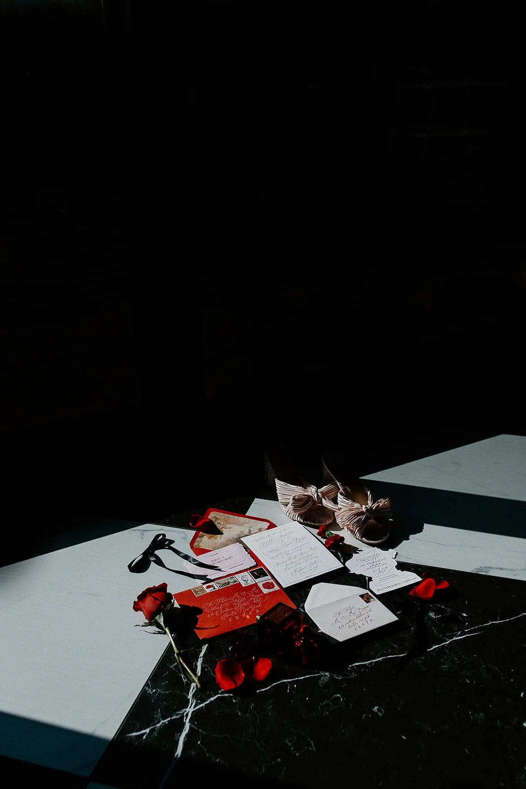 Romantic love notes, roses, and shoes on a table with sunlight casting shadows. Wedding invitation suite