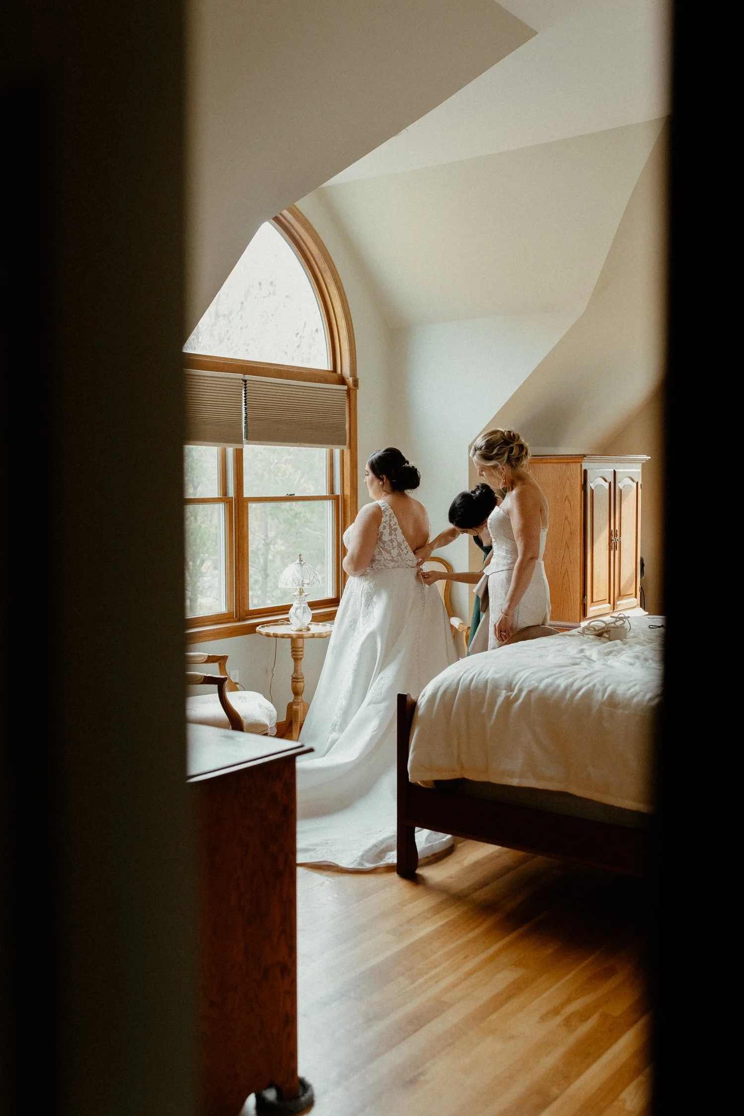 A mother helps her daughter into her wedding dress.