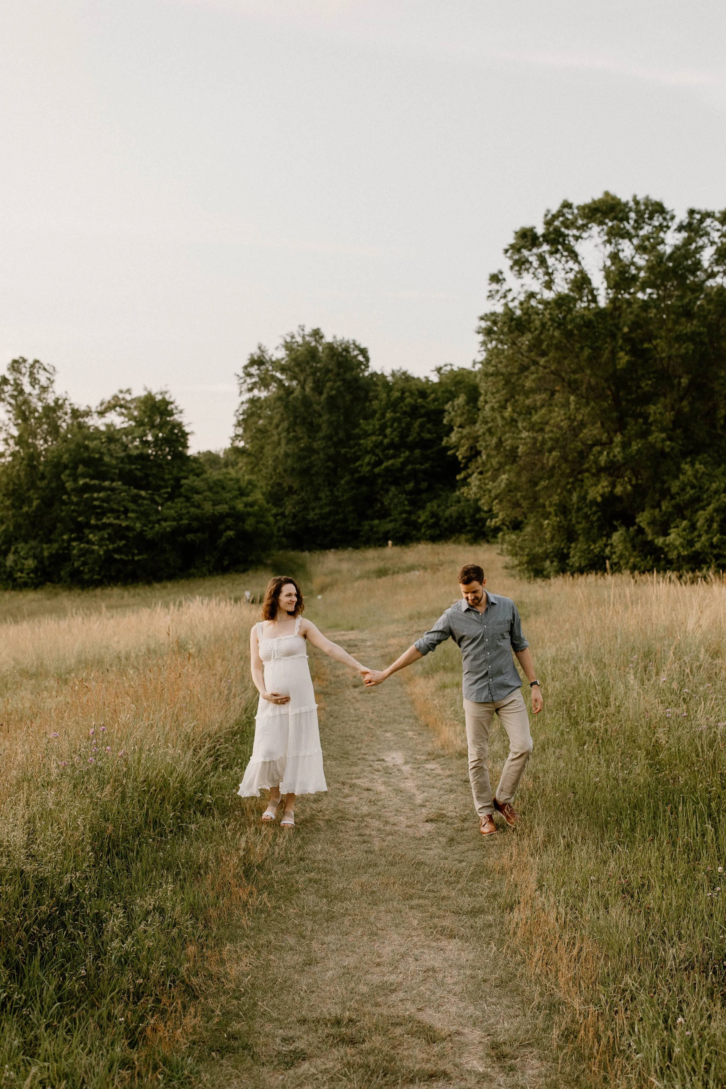 A pregnant wife walking the field with her husband.