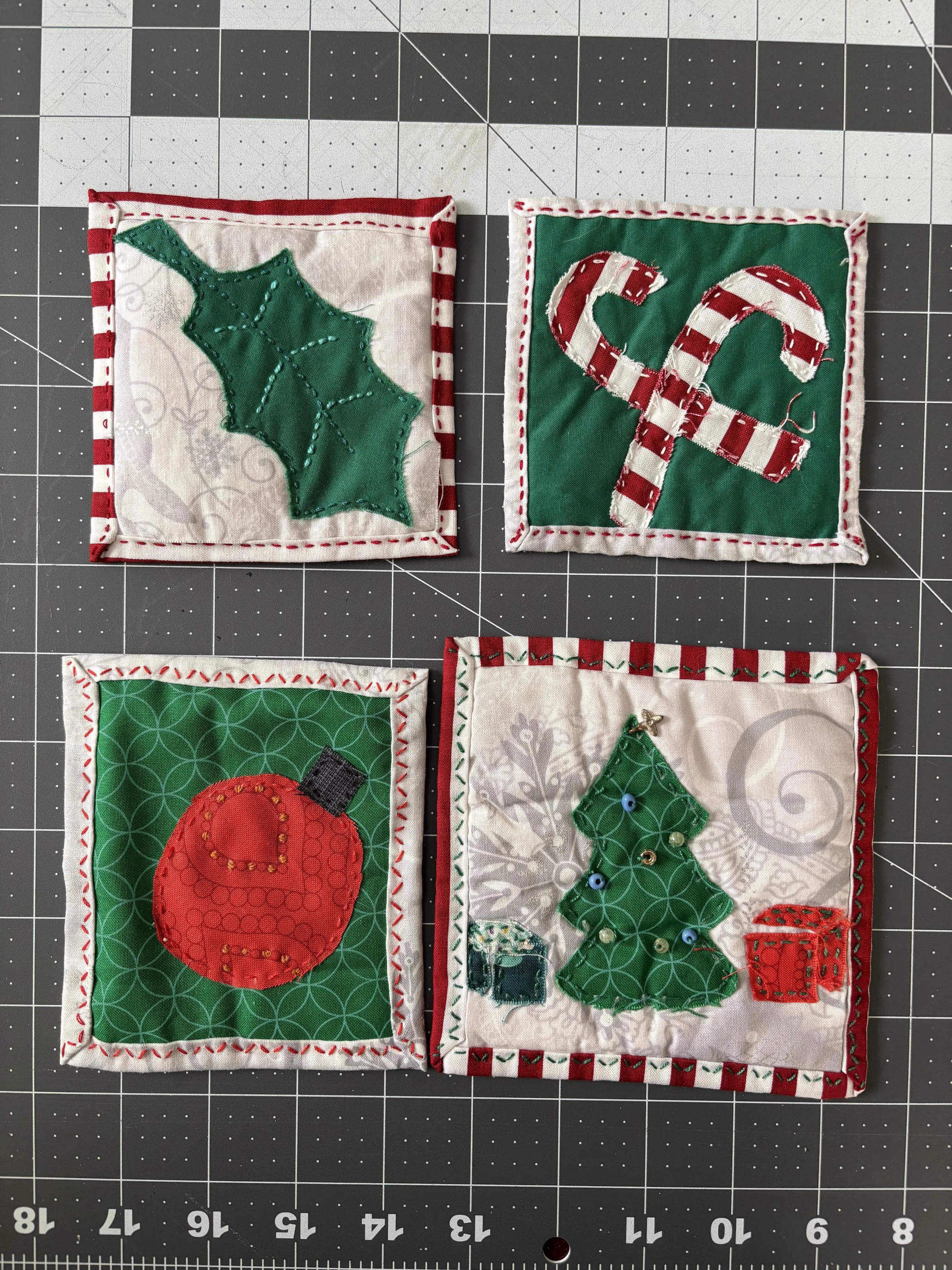 four hand-sewn Christmas-themed coasters (a holly leaf, a pair of candy canes, an ornament and a Christmas tree)