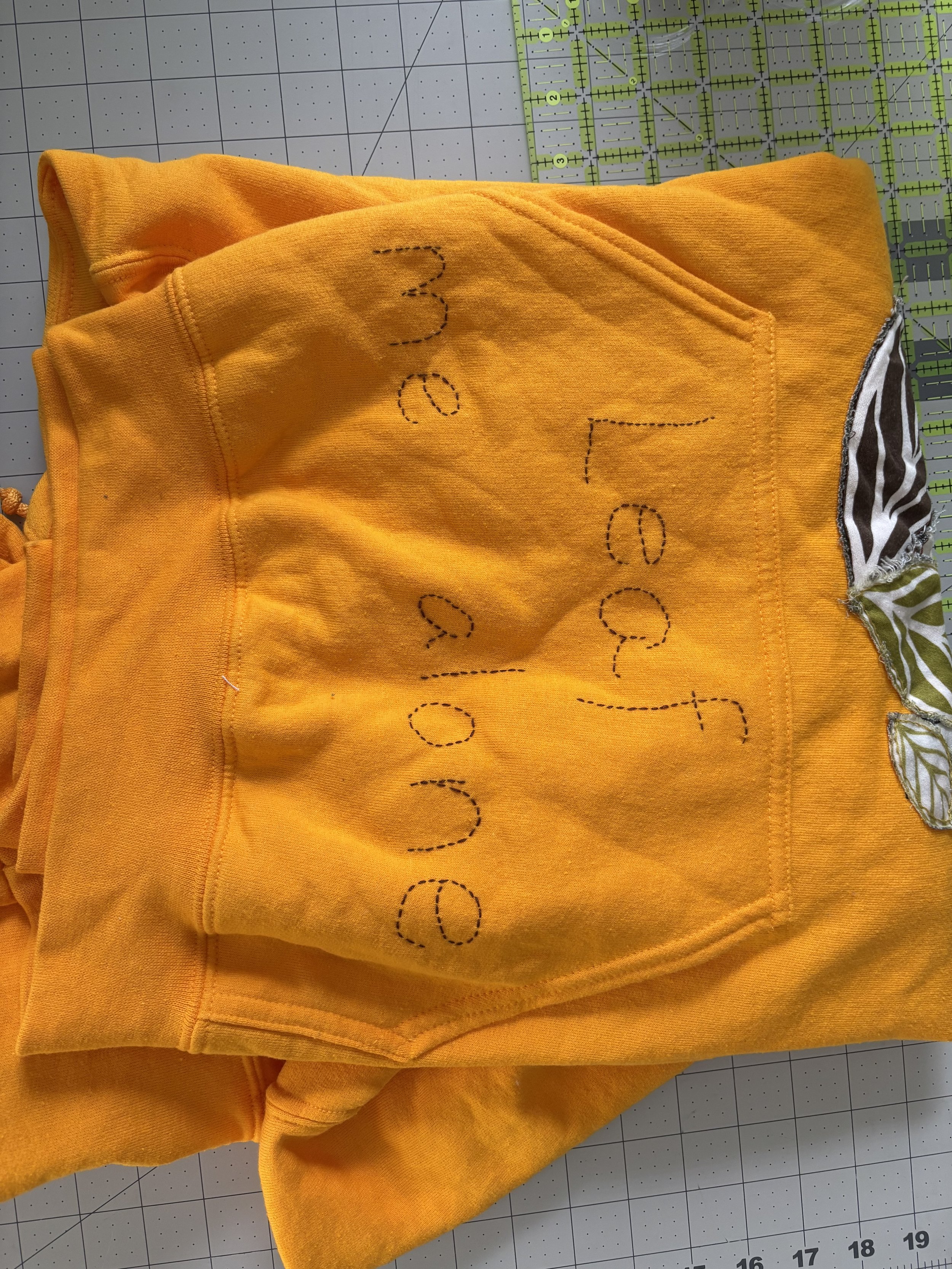 the words "Leaf Me Alone" embroidered on a yellow hoodie
