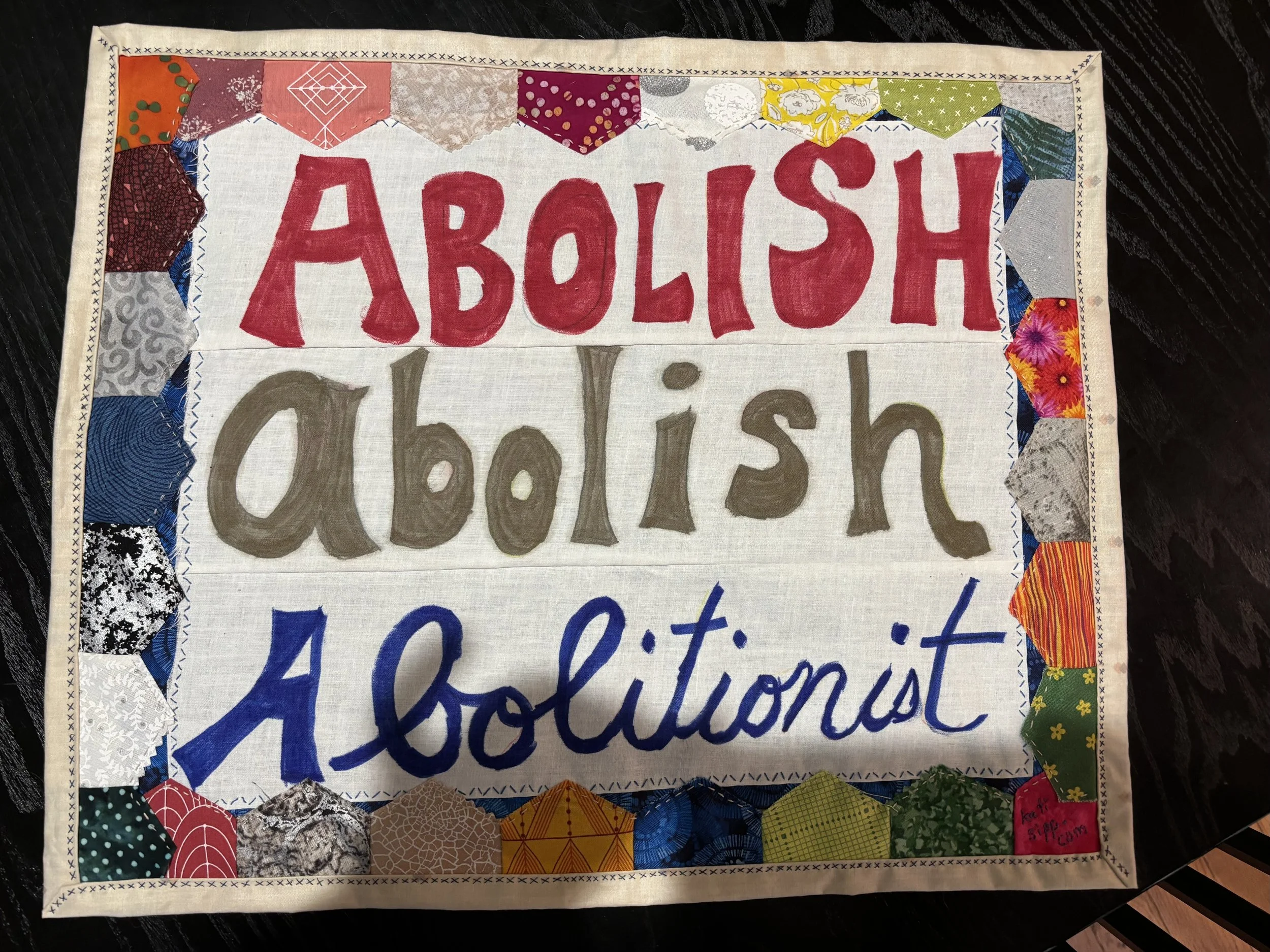 a hand-sewn wall hanging that reads "Abolish/Abolish/Abolitionist"