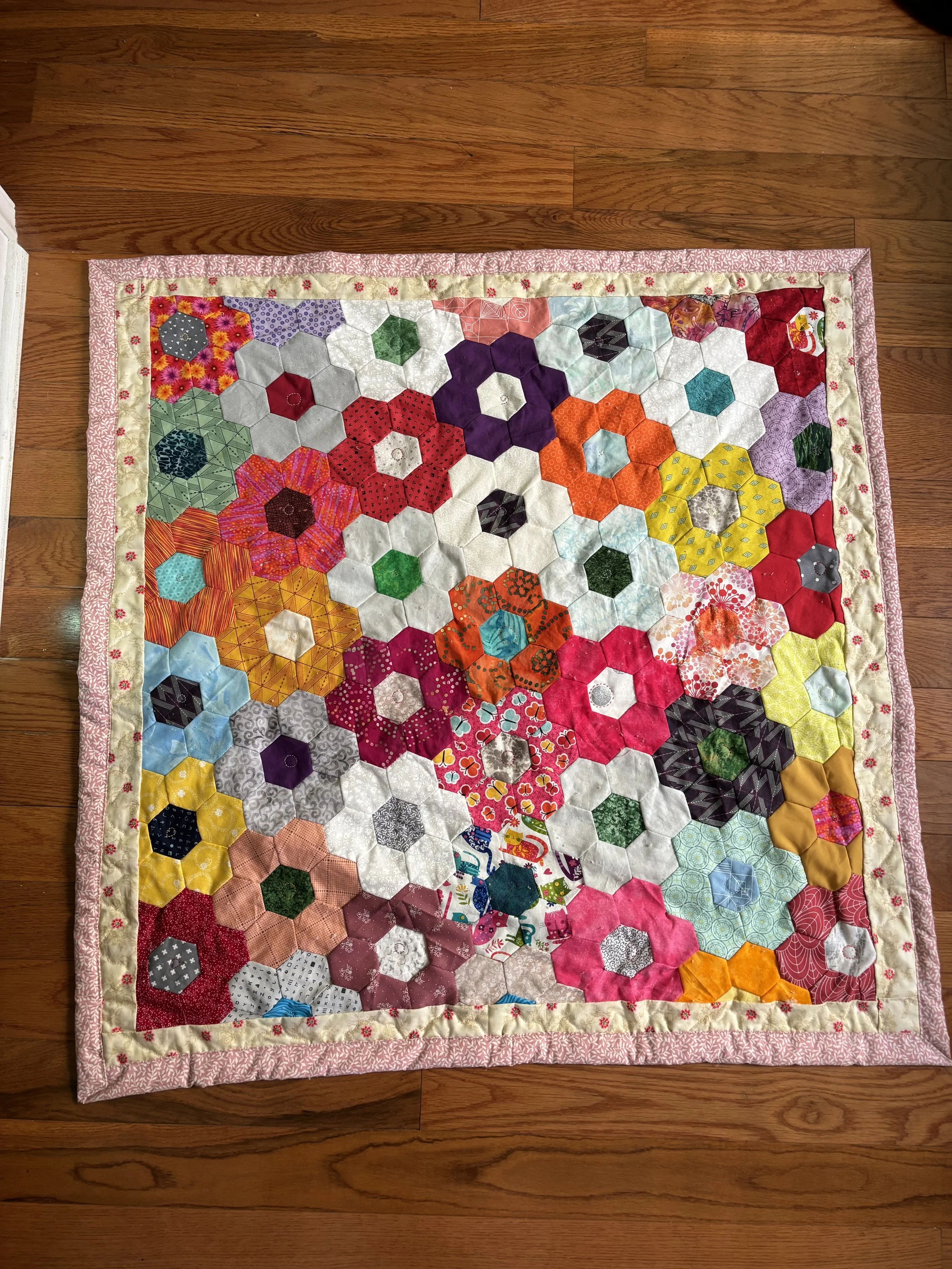a baby quilt made of quilted flowers sewn from multi-colored fabric