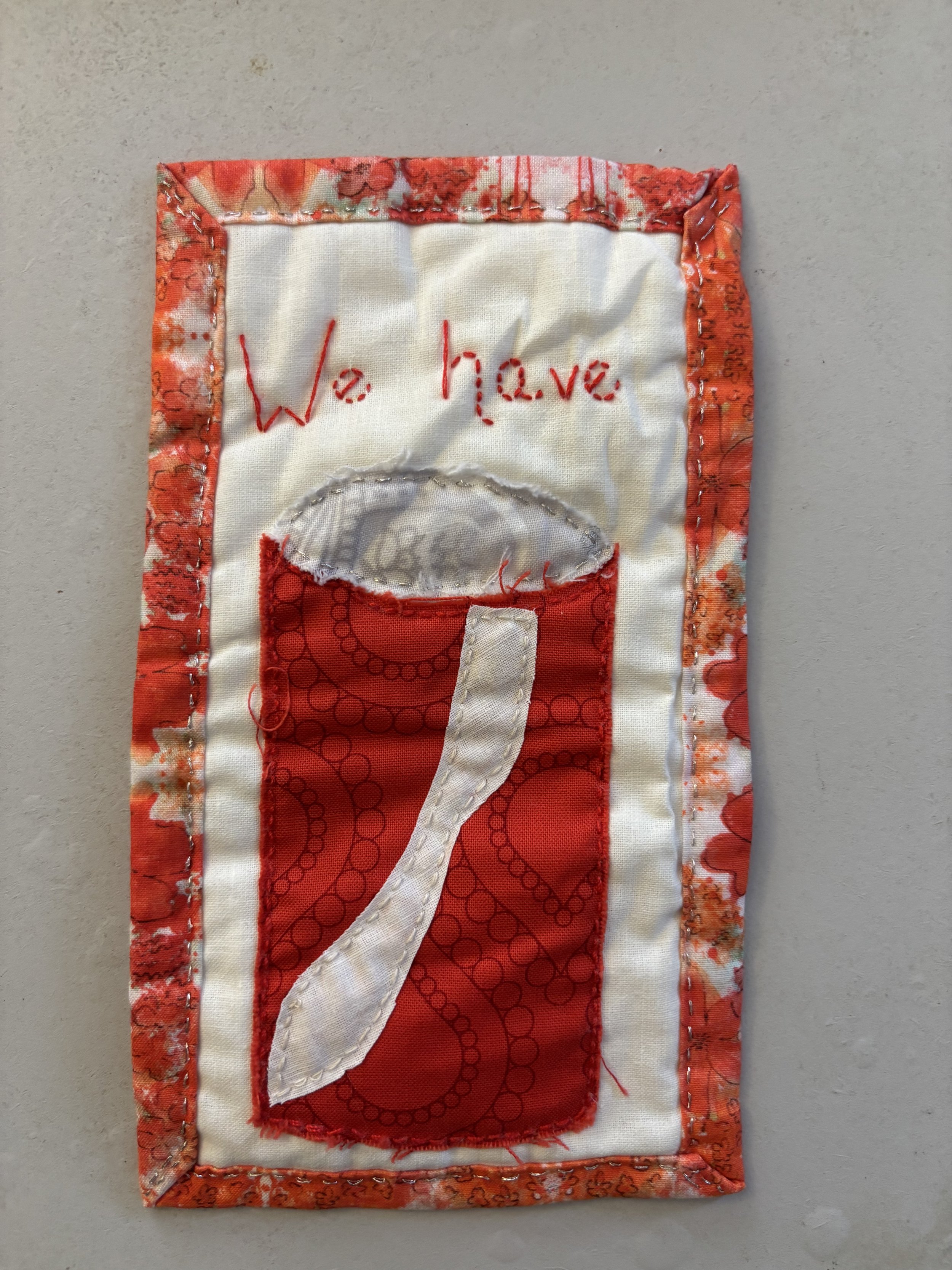 a small fabric wall hanging that says "We have" and contains a picture of a soda can.