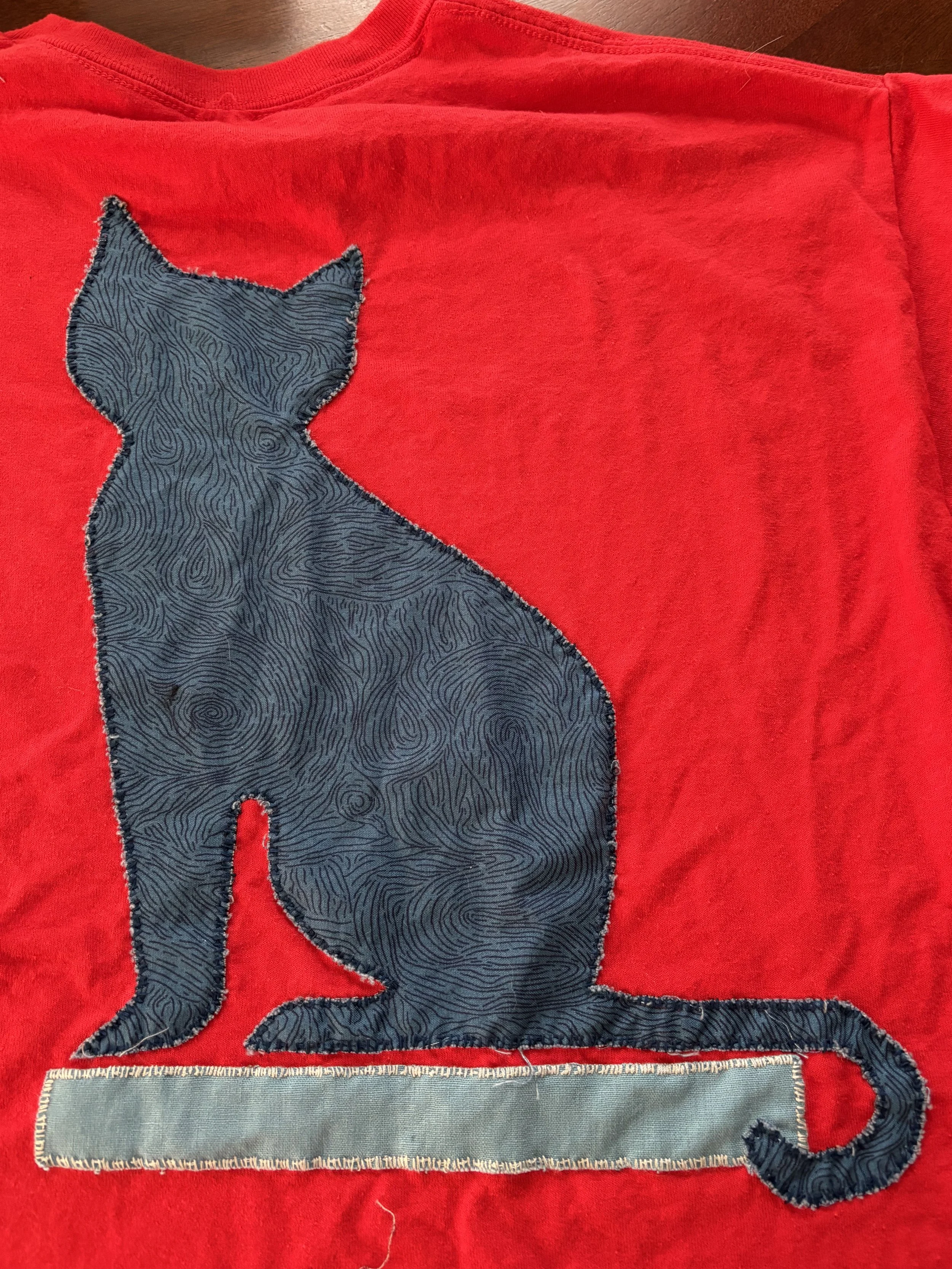 detail of cat appliqué on back of red t-shirt