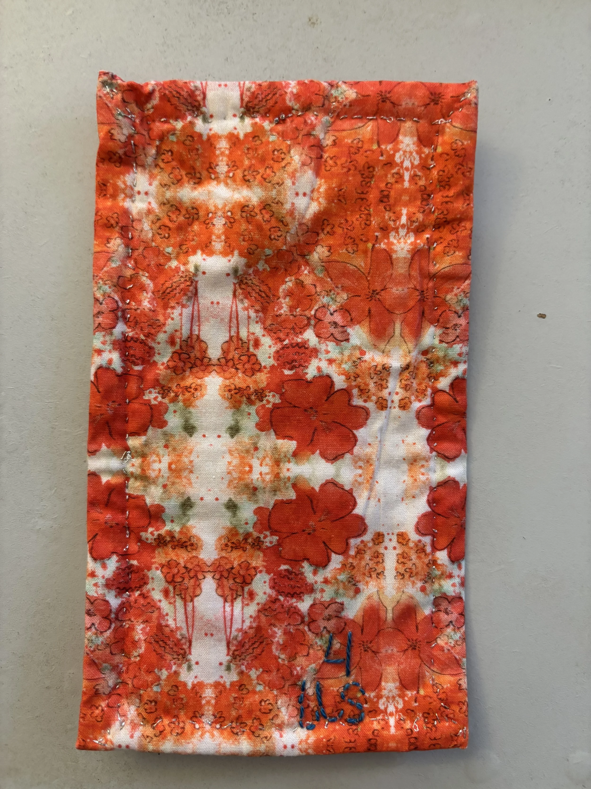 the quilted back of a small fabric object, fabric is a pattern of orange flowers