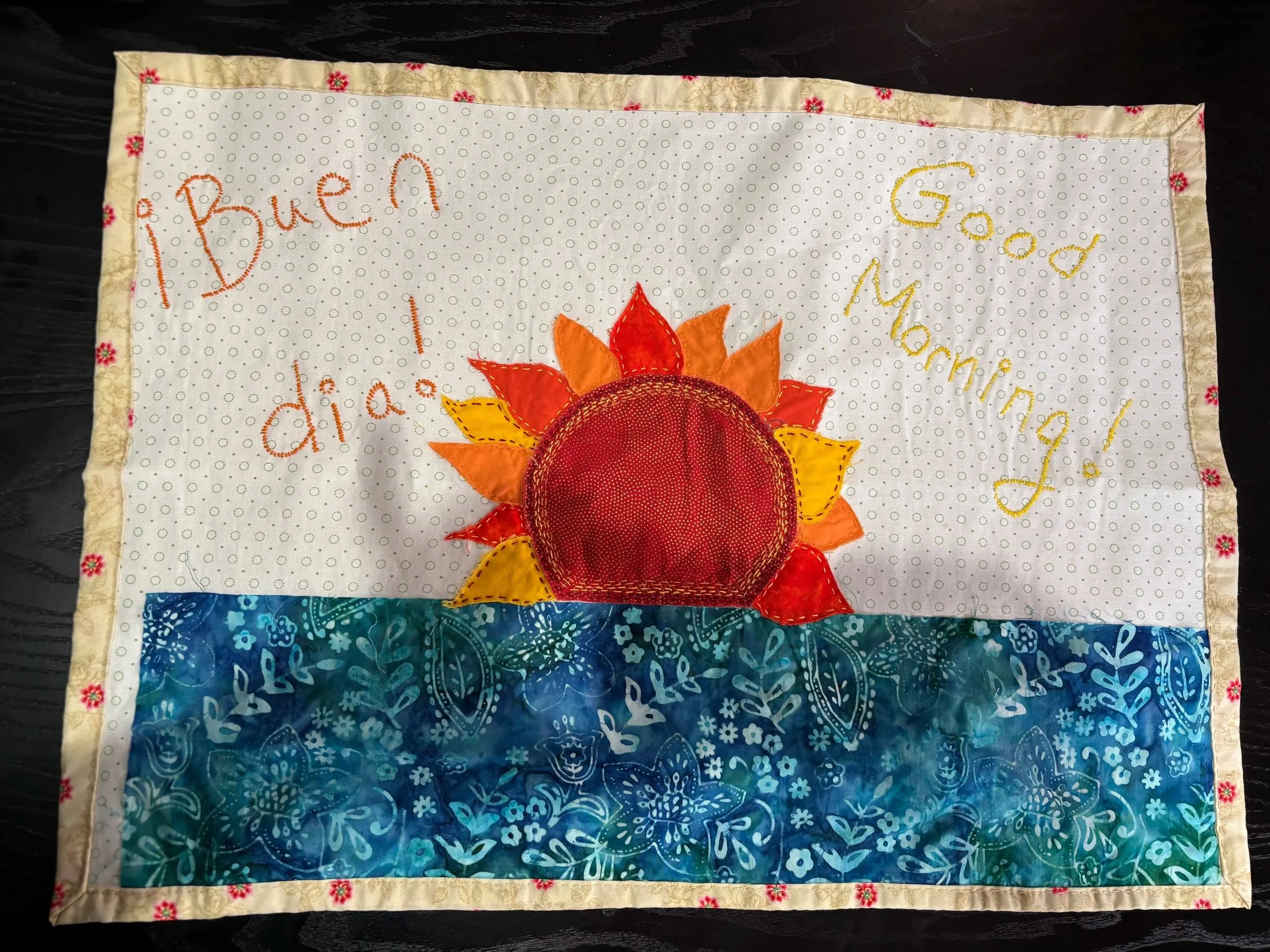 fabric wall hanging with a picture of a sunrise over the ocean
